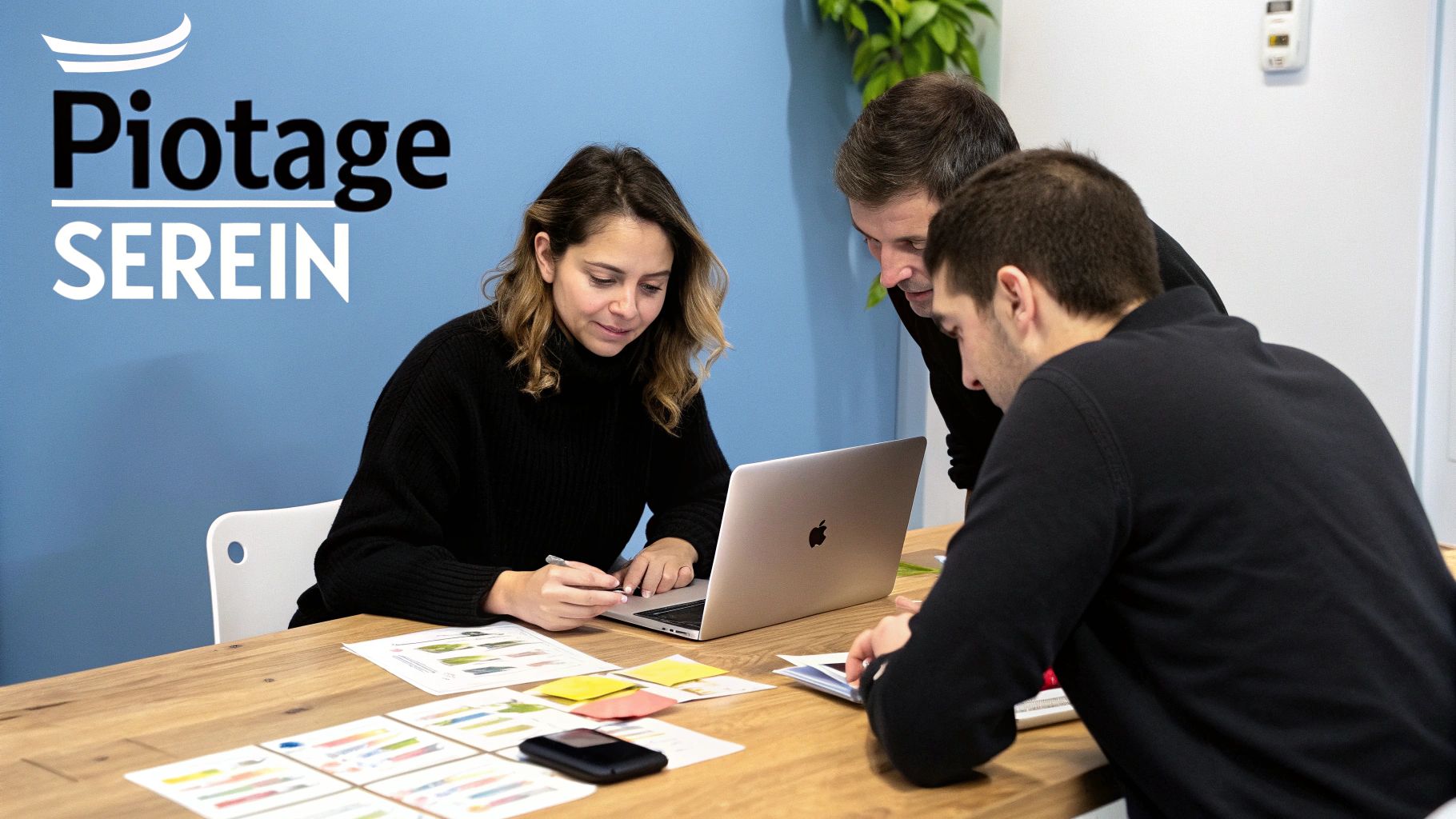 Trois personnes collaborent activement autour d'un ordinateur portable et de documents lors d'une réunion.