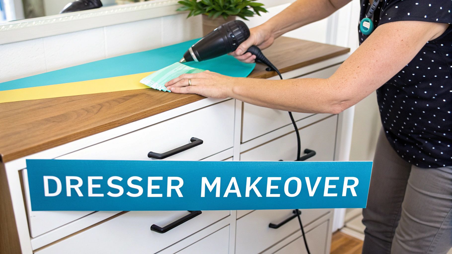 A person applies blue and yellow decorative film to a white dresser top with a heat gun, transforming its look.