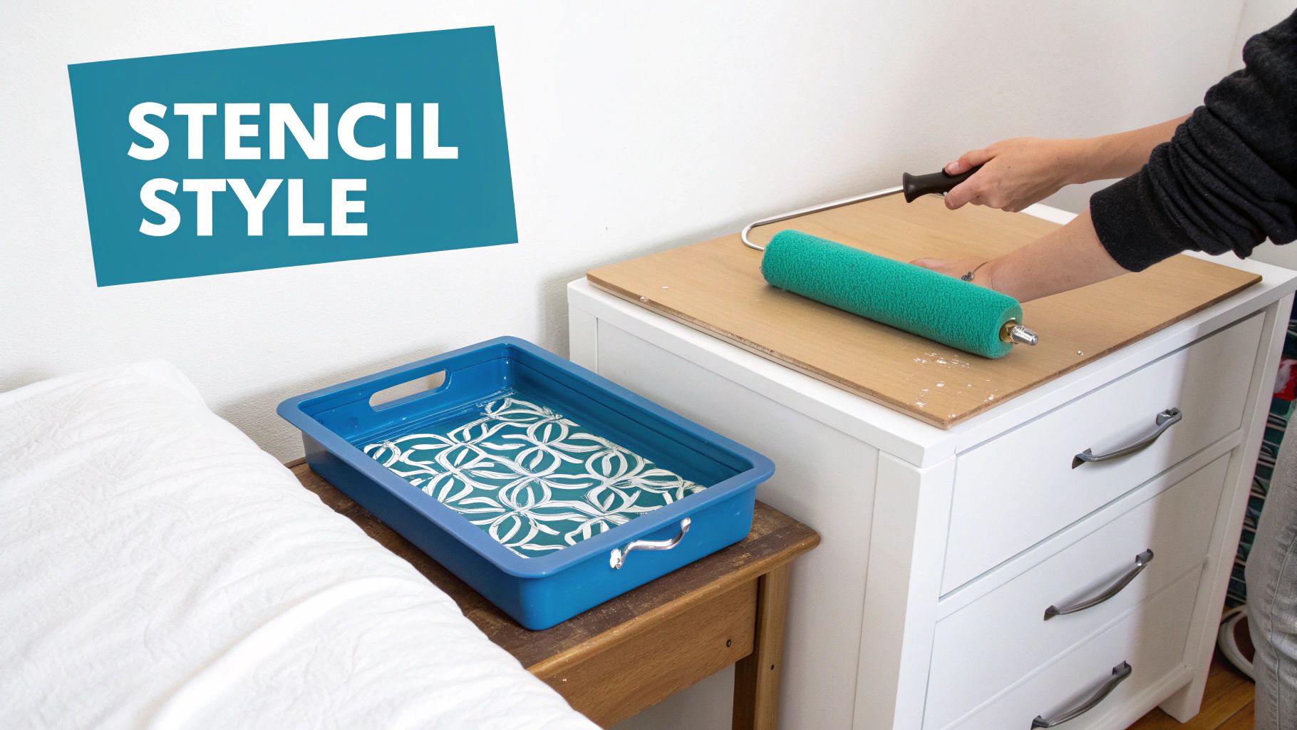 Person stenciling a pattern using a paint roller, with a finished stenciled tray and a white dresser.