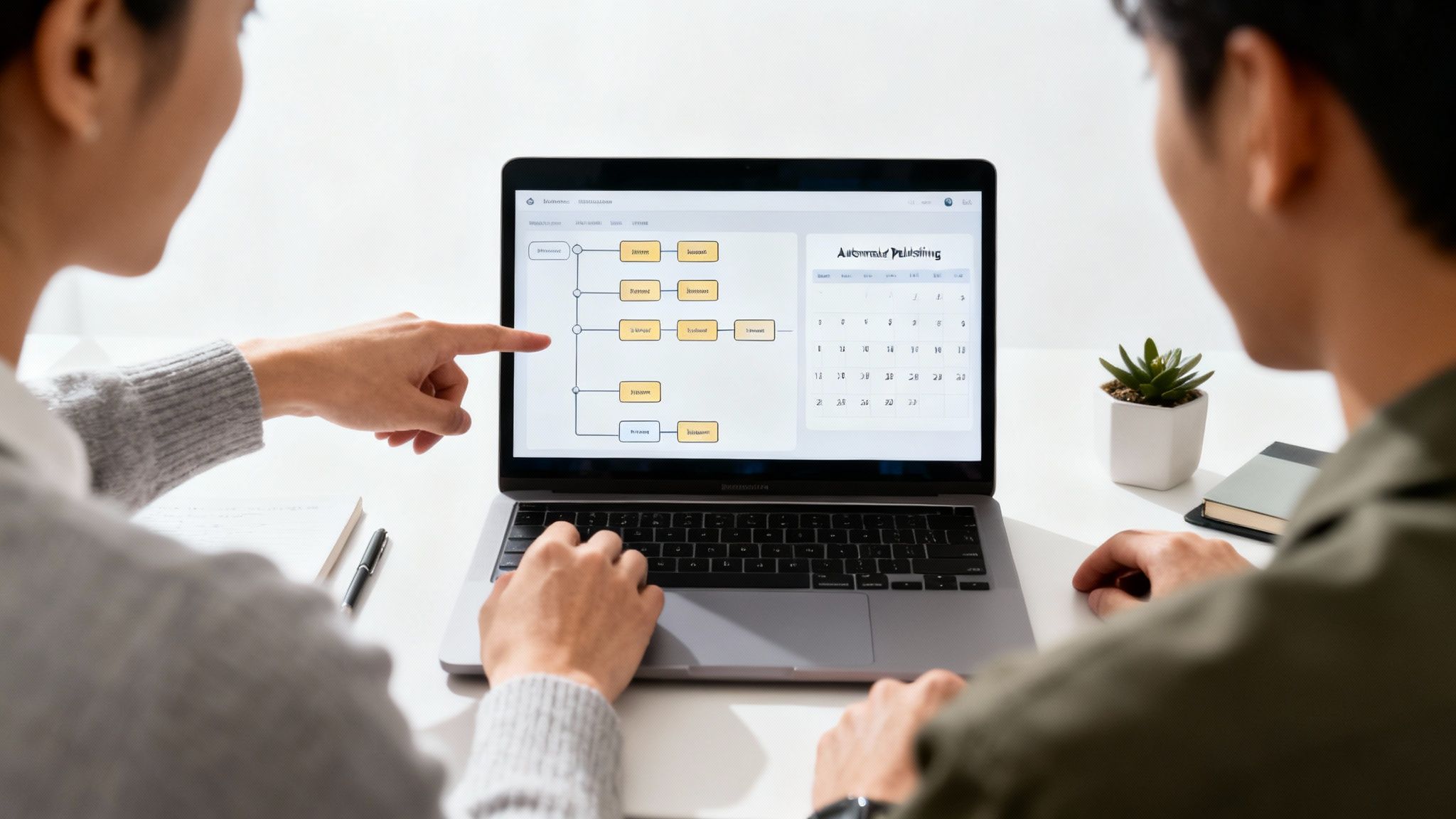 Two people collaborate on a laptop, discussing a digital flowchart and calendar for content strategy.