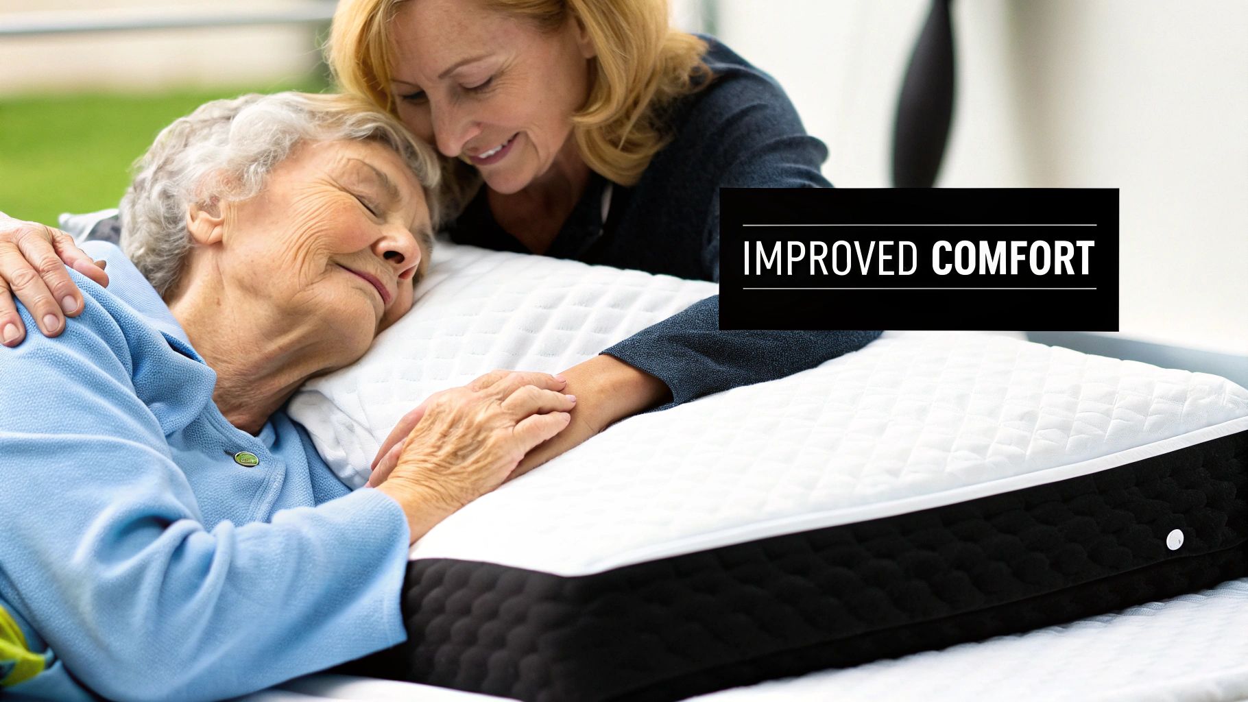 Elderly woman sleeping peacefully on a specialized mattress, with a caregiver smiling and holding her hand.