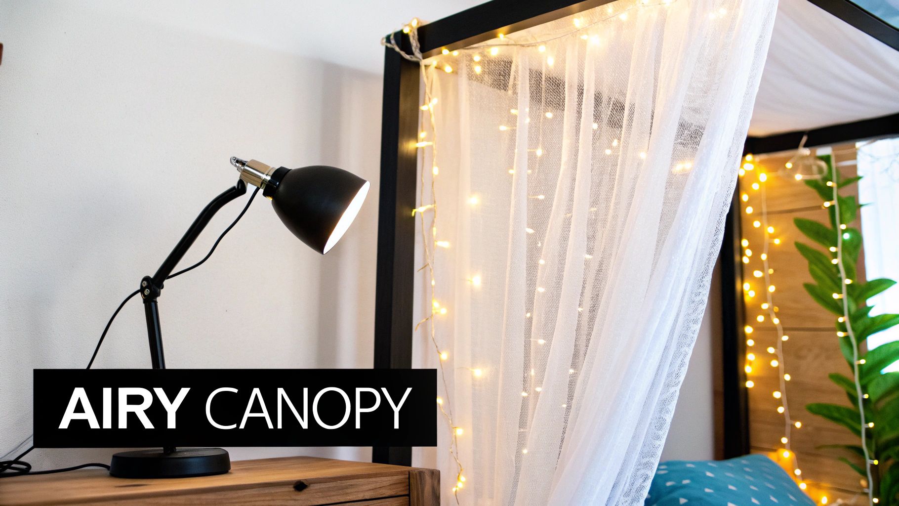 A black desk lamp on a wooden nightstand next to a canopy bed with sheer white curtains and warm string lights.