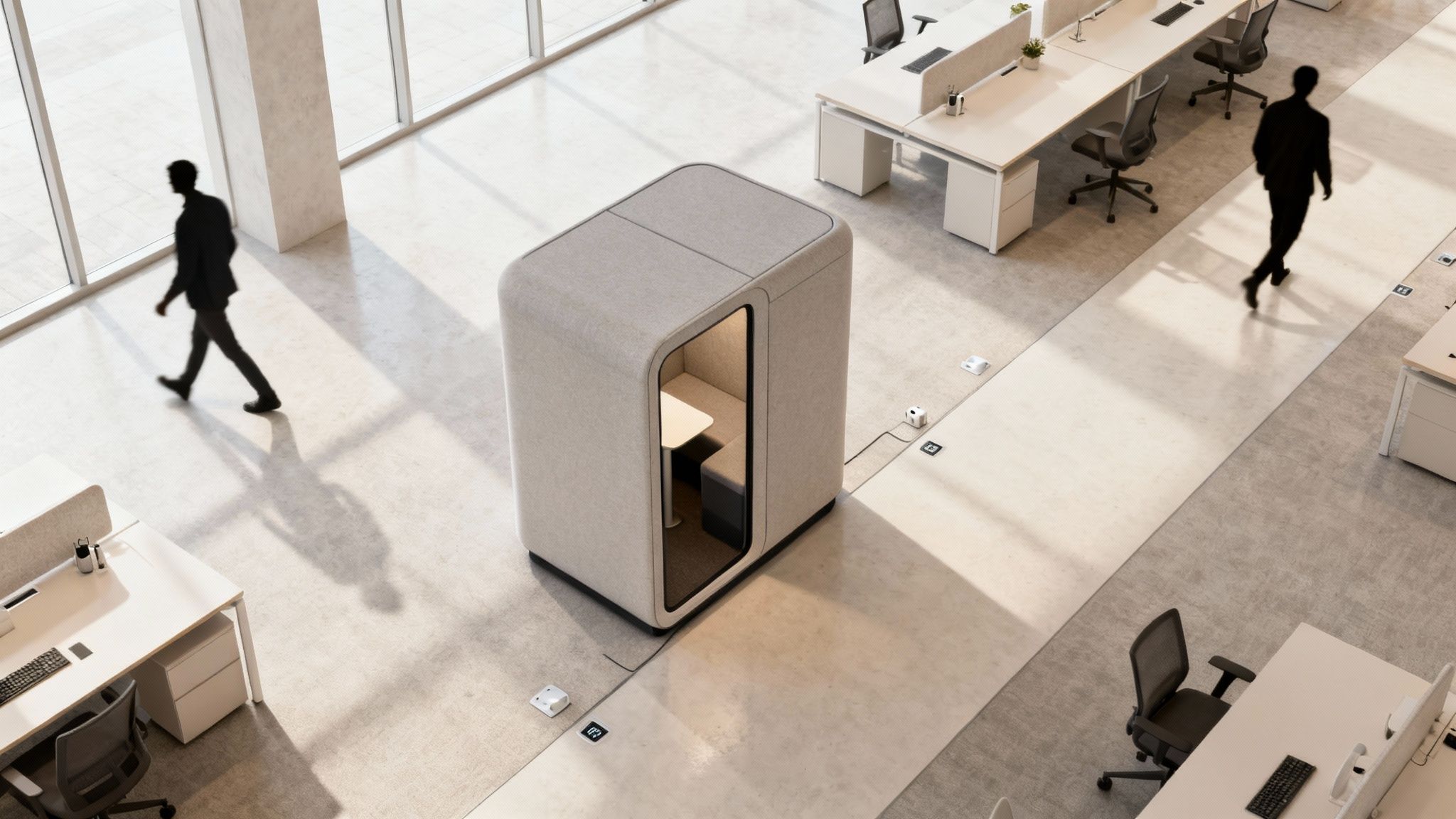 Overhead view of a modern open-plan office with a beige meeting pod, desks, and people walking.