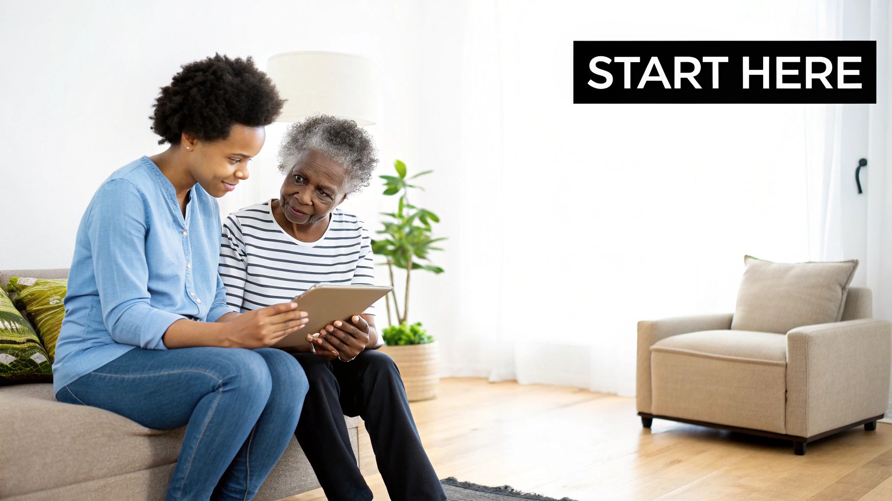 A young woman assists an elderly woman using a tablet on a sofa in a bright living room.