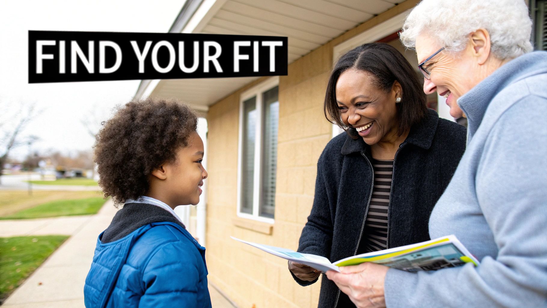 Three people, including a boy and two women, smiling and looking at a brochure outside a home.