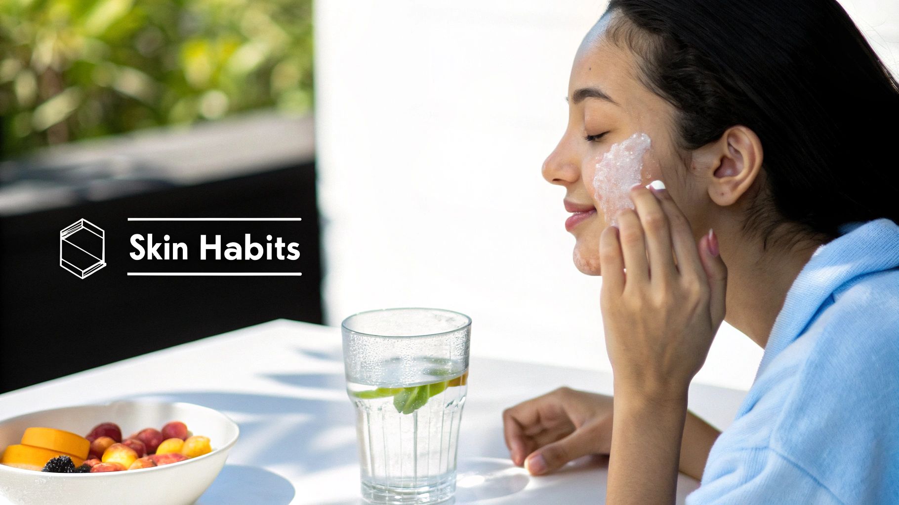 A woman applies a face mask, with fruit and infused water on a table, promoting 'Skin Habits'.