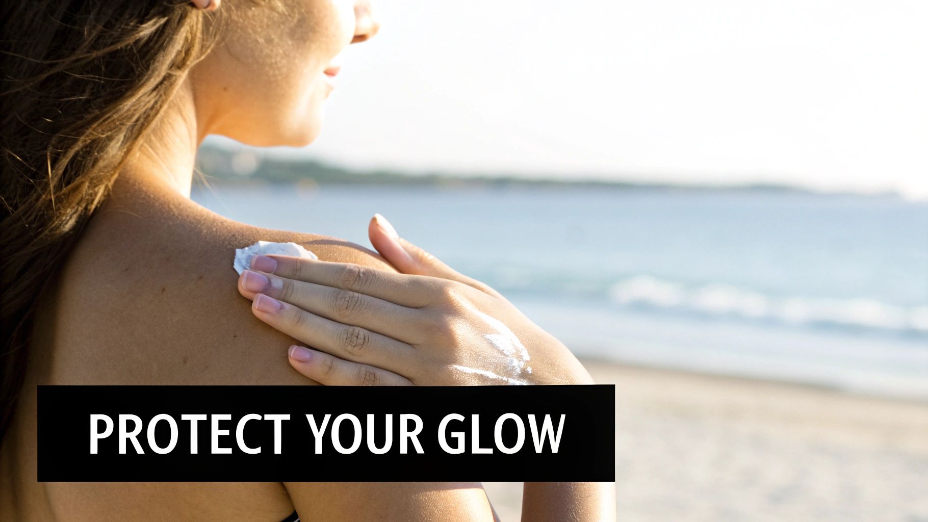 A woman applies sunscreen to her shoulder at a sunny beach, protecting her skin.