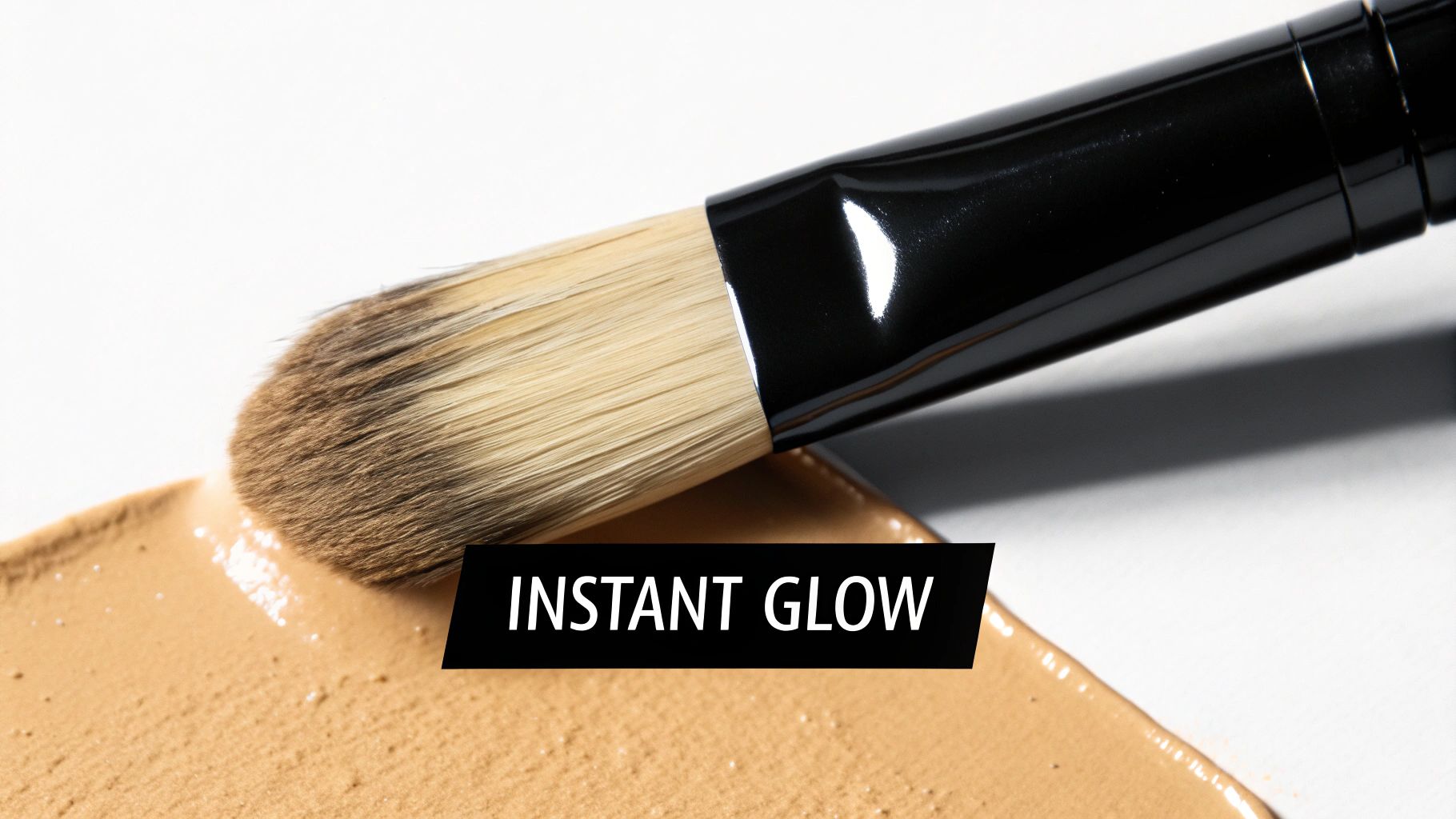 A makeup brush spreads beige liquid foundation on a white surface, featuring 'INSTANT GLOW' text.