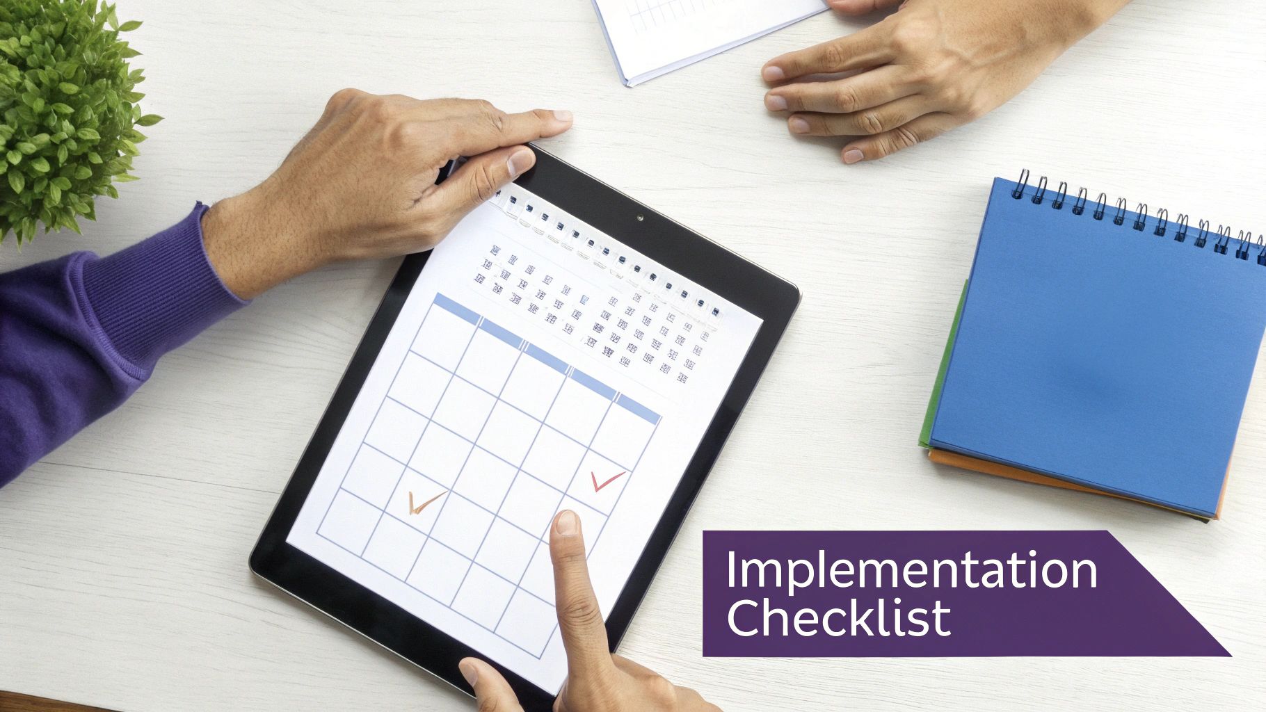Two people collaboratively reviewing an implementation checklist on a tablet, with notebooks and a plant.