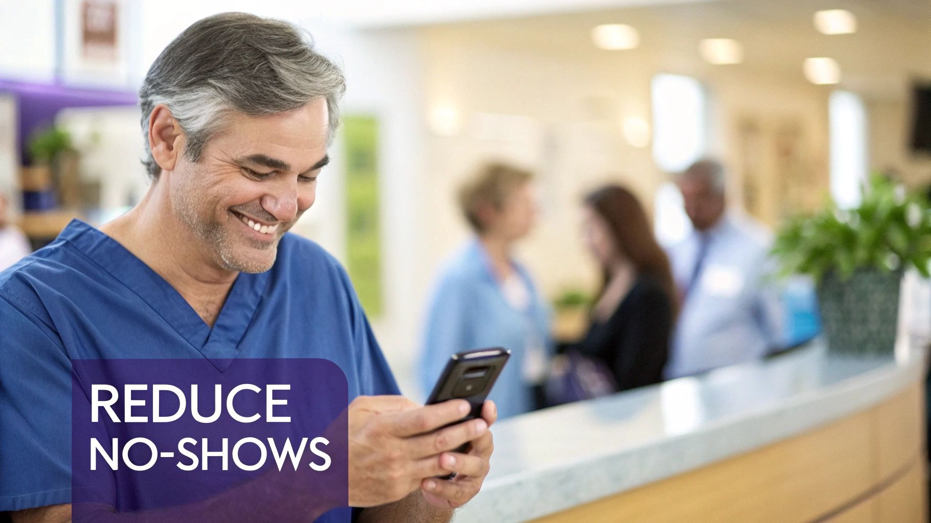 A smiling male medical professional in blue scrubs checks his smartphone in a clinic reception area.