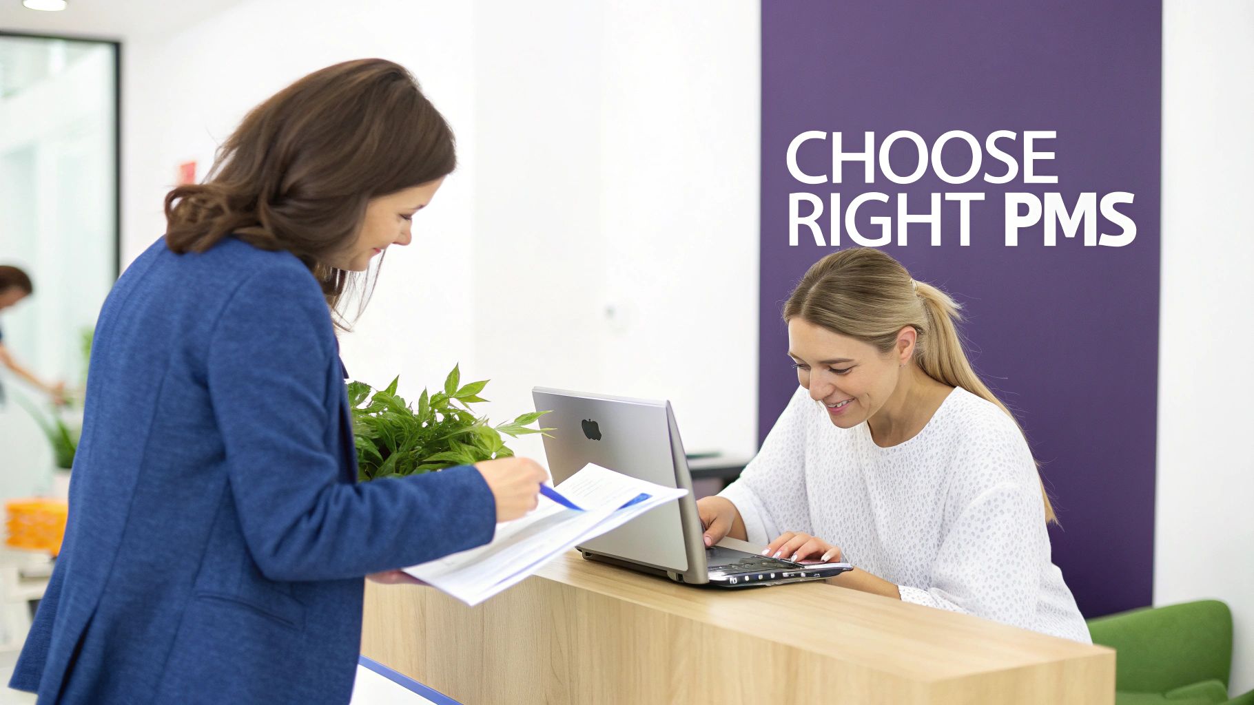 Two women at an office reception desk, one signing documents while the other uses a laptop.