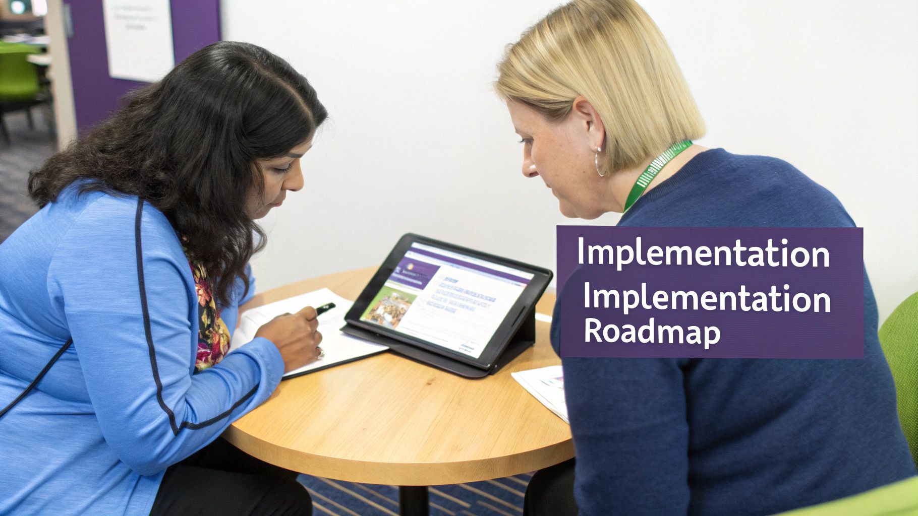Two women collaborate on an implementation roadmap, reviewing content on a tablet and taking notes.