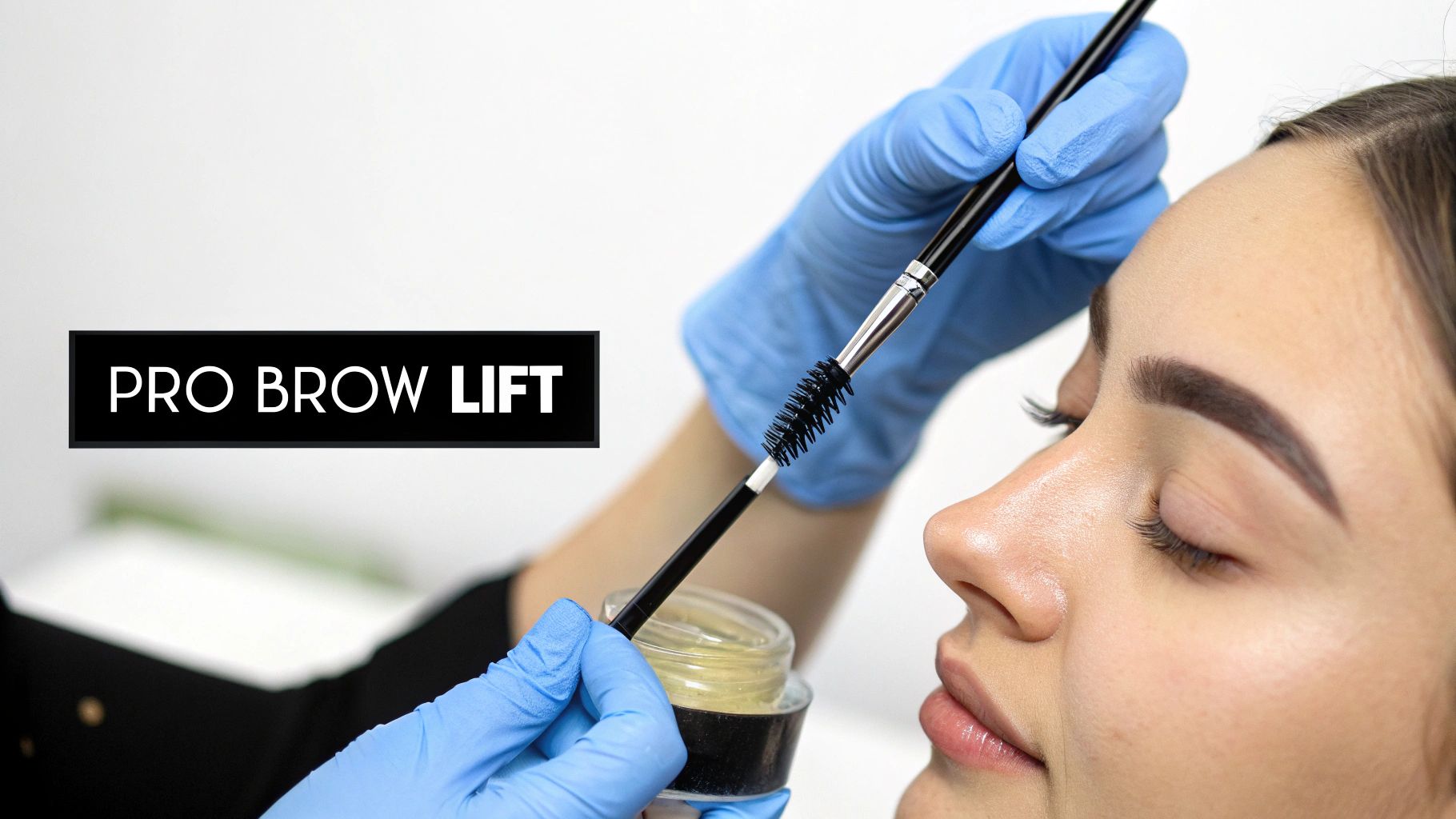 Close-up of a beauty professional applying product with a brush for a brow lift treatment.