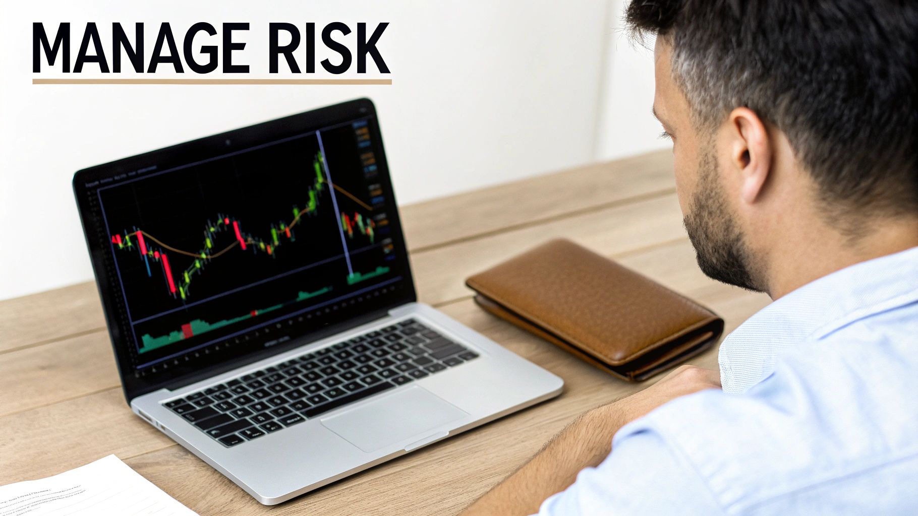 A man views financial charts on a laptop, with text 'MANAGE RISK', a wallet, and papers on a wooden desk.