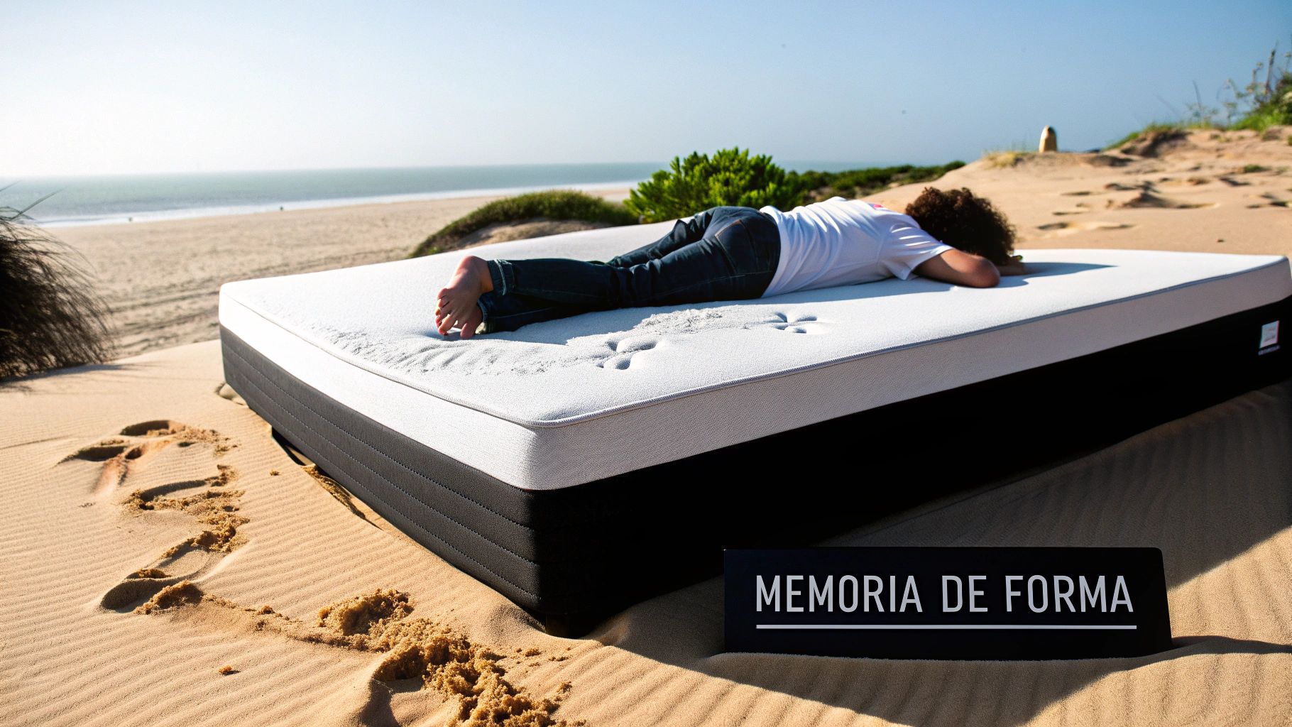 Persona durmiendo boca abajo en un colchón viscoelástico sobre la arena de la playa con el mar de fondo.
