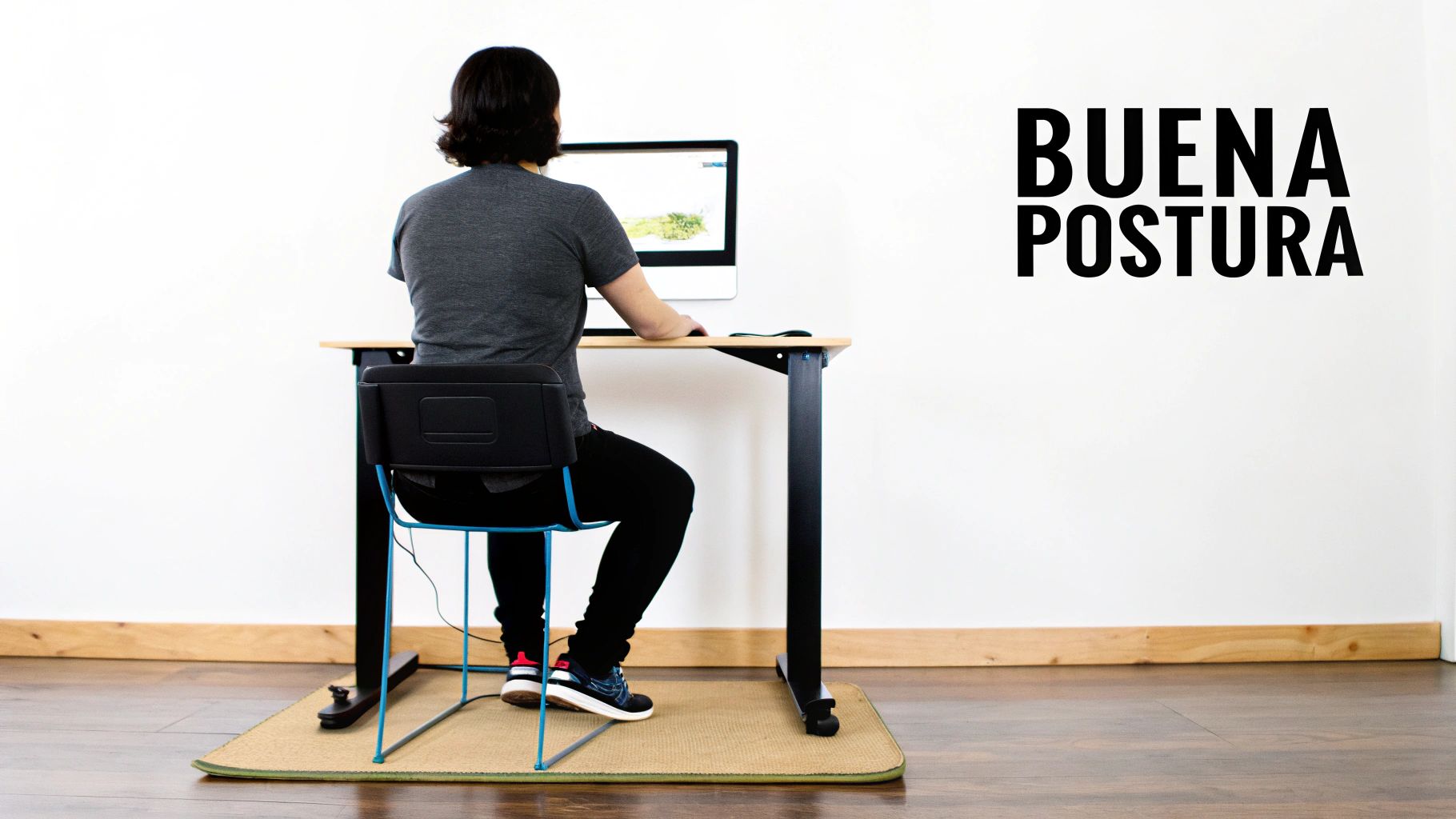 Vista trasera de una persona con buena postura trabajando en un escritorio con ordenador.