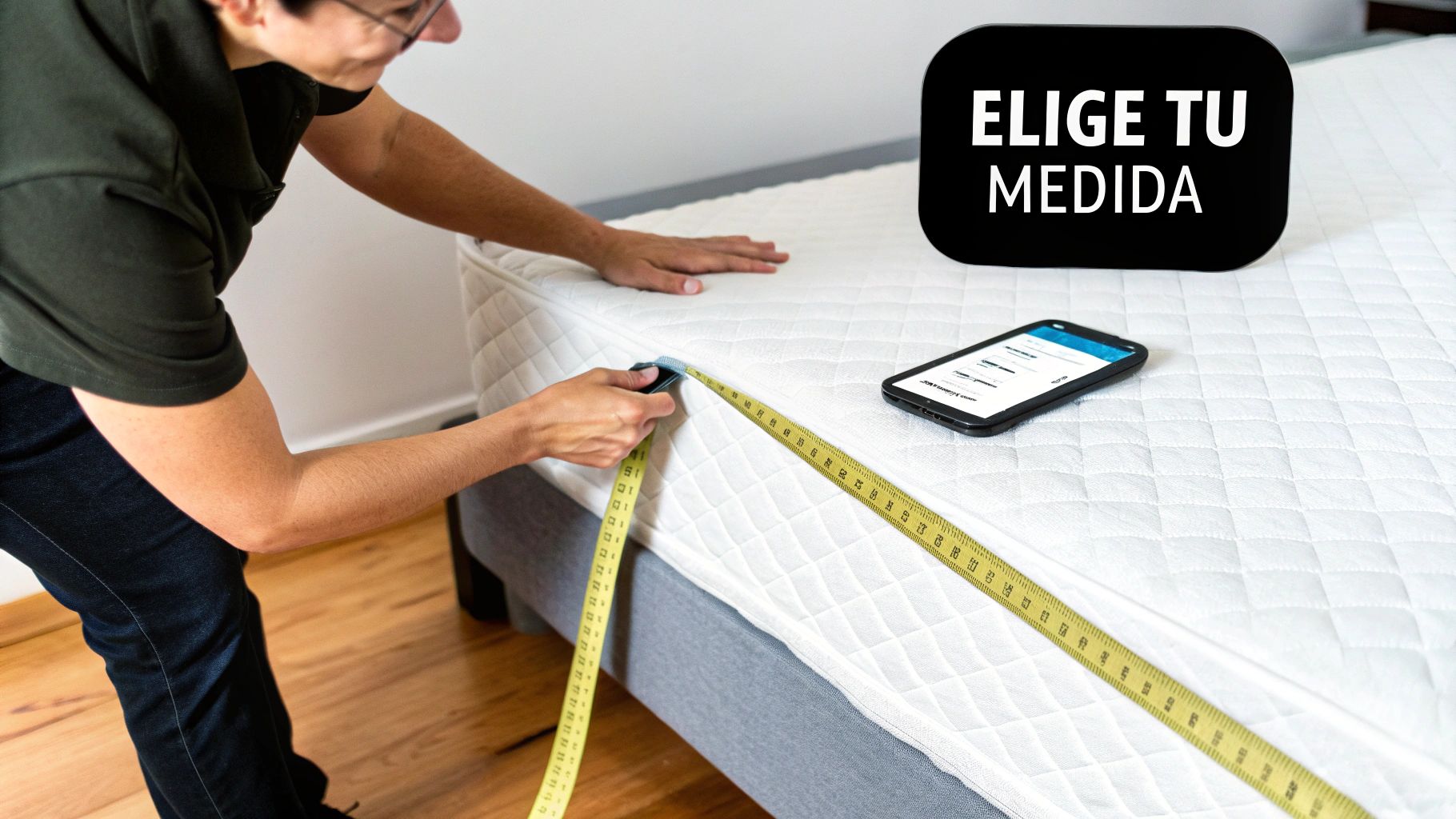 Una persona mide un colchón blanco con una cinta métrica amarilla, cerca de un teléfono y un cartel que dice 'ELIGE TU MEDIDA'.