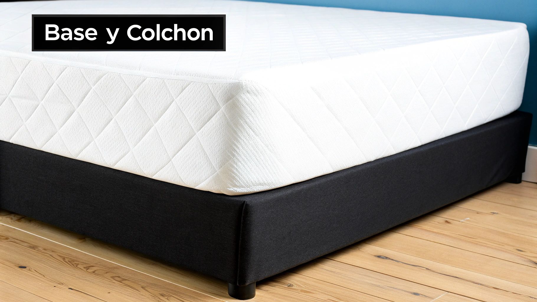 Colchón blanco acolchado con patrón de rombos sobre una base de cama negra, en un suelo de madera.