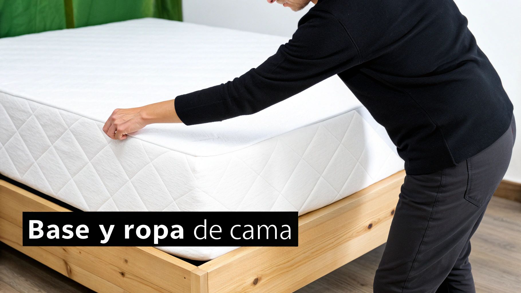 Una persona ajusta una sábana bajera o protector de colchón blanco en una cama con base de madera.
