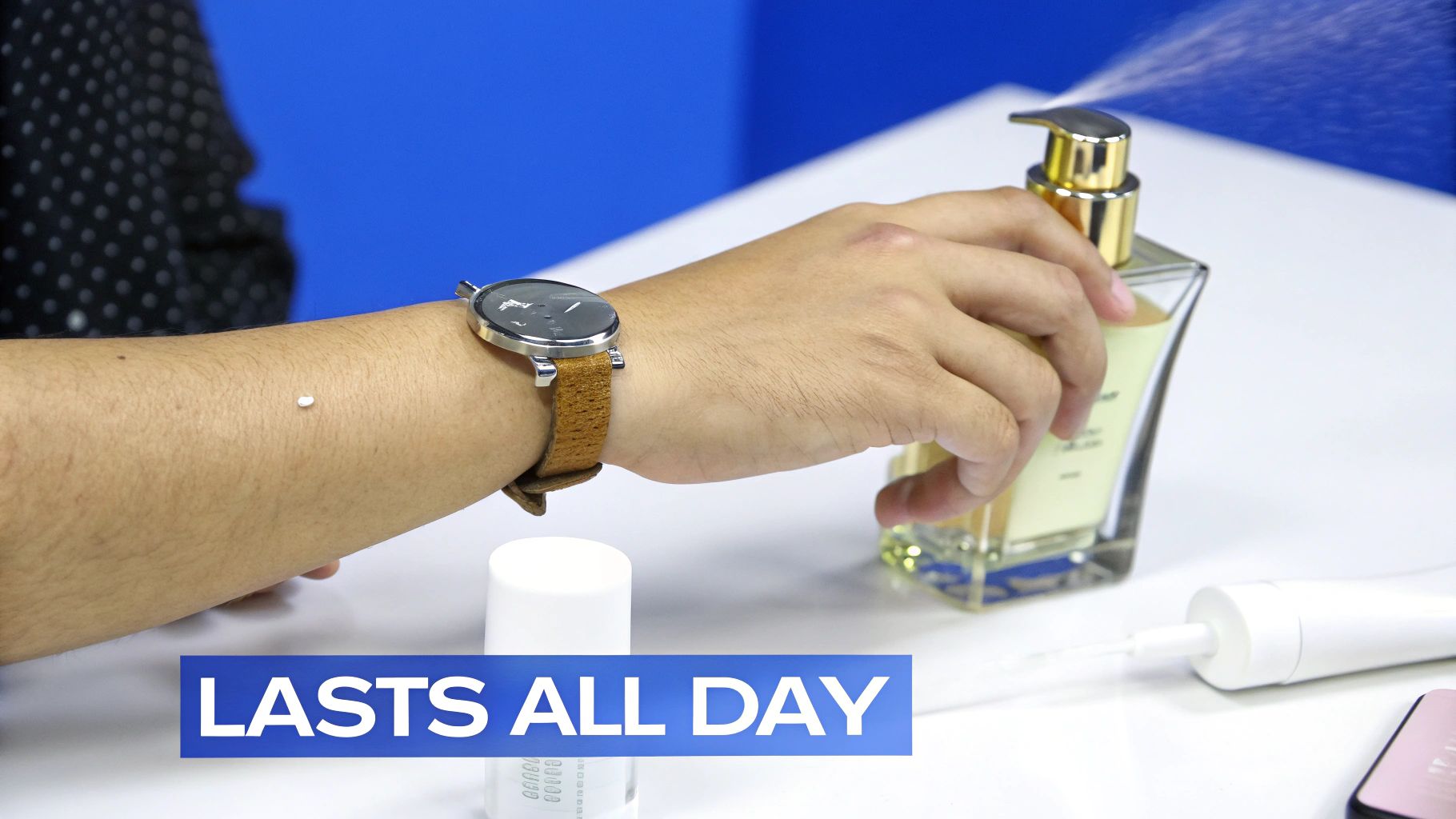 A person's arm with a watch, applying a fragrance that sprays, with a small white bead on the skin.