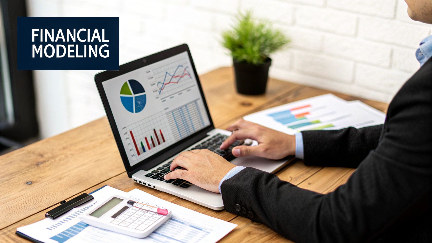 A person working on a laptop with complex charts and graphs displayed on the screen.