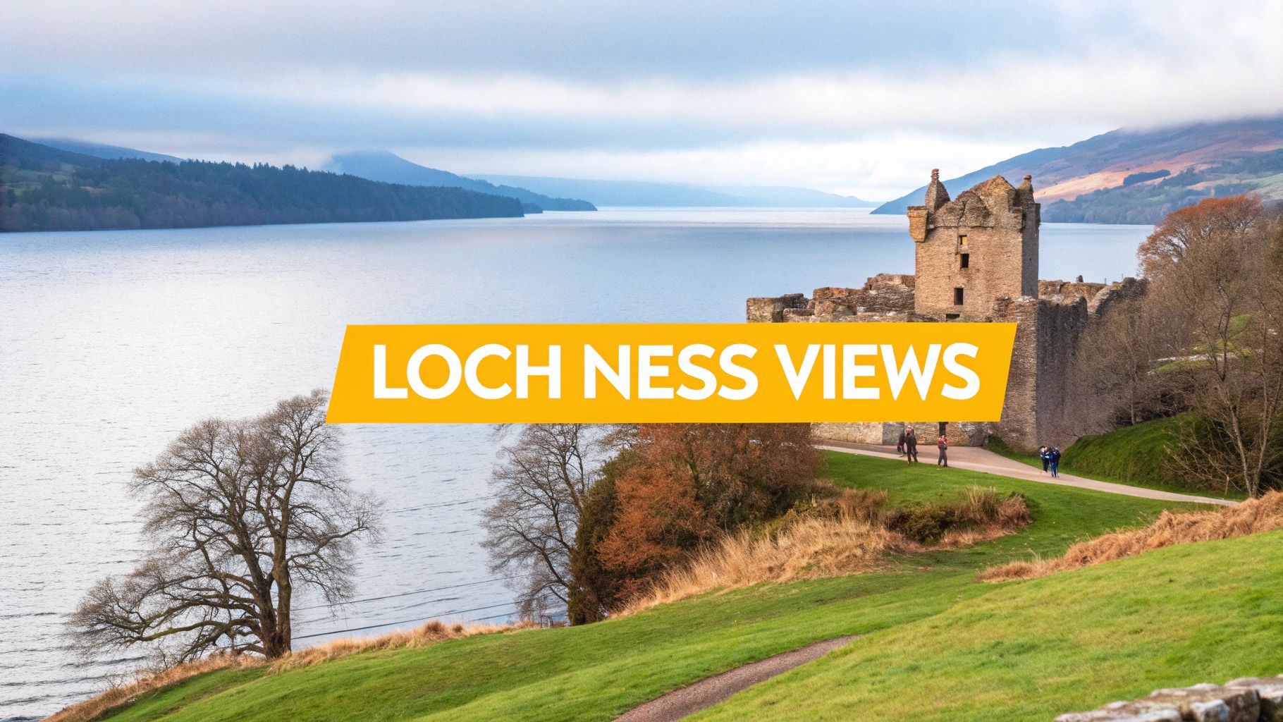 Urquhart Castle ruins overlooking the vast Loch Ness, surrounded by mountains under a cloudy Scottish sky.