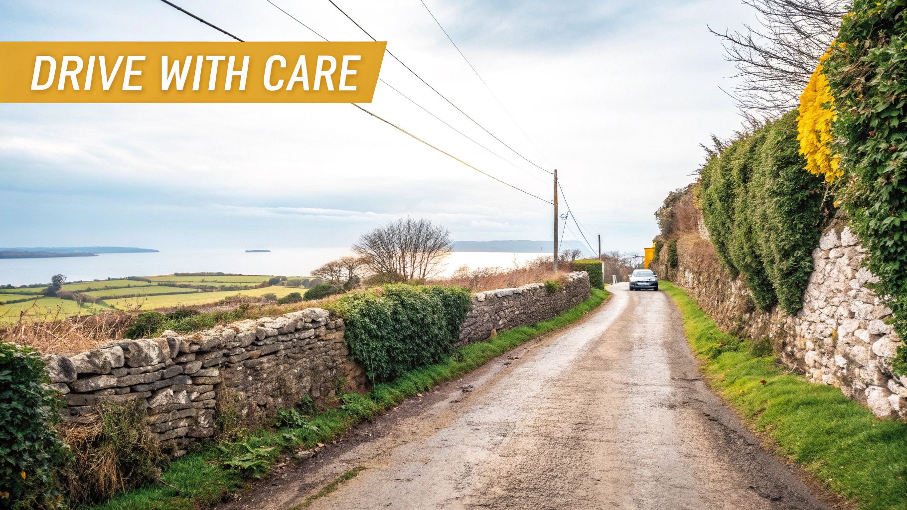 Your Guide to Driving in Eire and Exploring Ireland by Car 5 A car drives on a narrow country road with stone walls, hedges, and a scenic bay view.