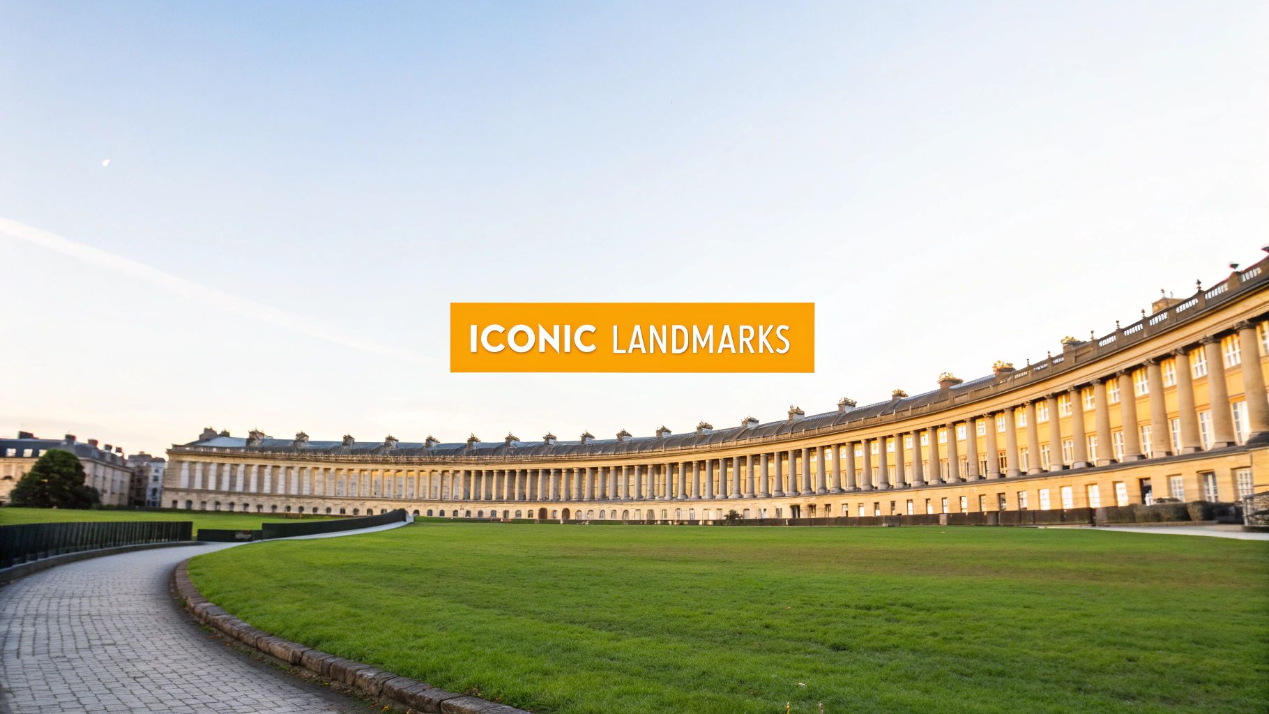 The iconic Royal Crescent in Bath, a curved Georgian architectural marvel, with a vast green lawn and paved path under a clear sky.
