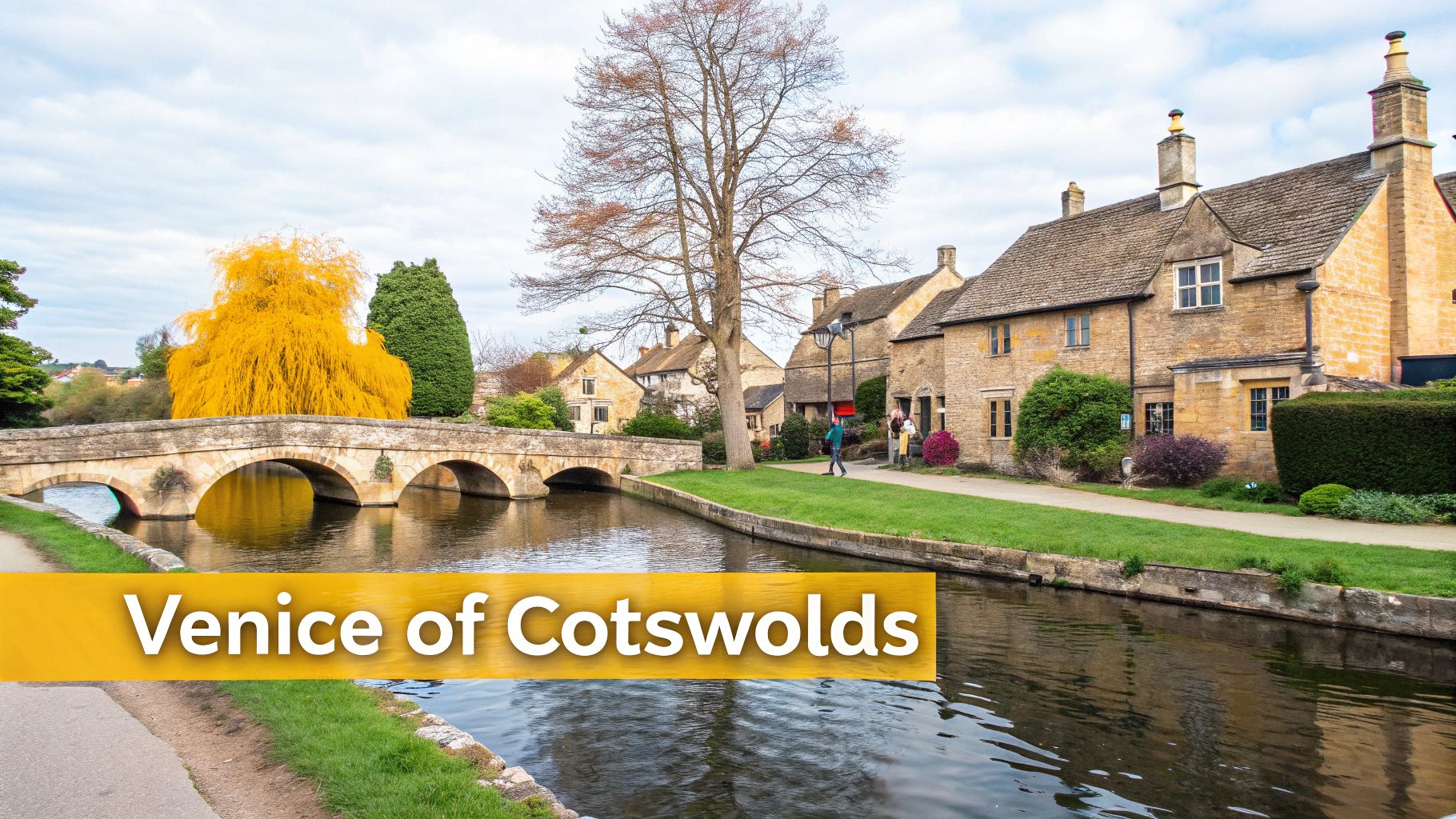 A scenic view of a stone bridge over a tranquil river flowing through a charming Cotswolds village.