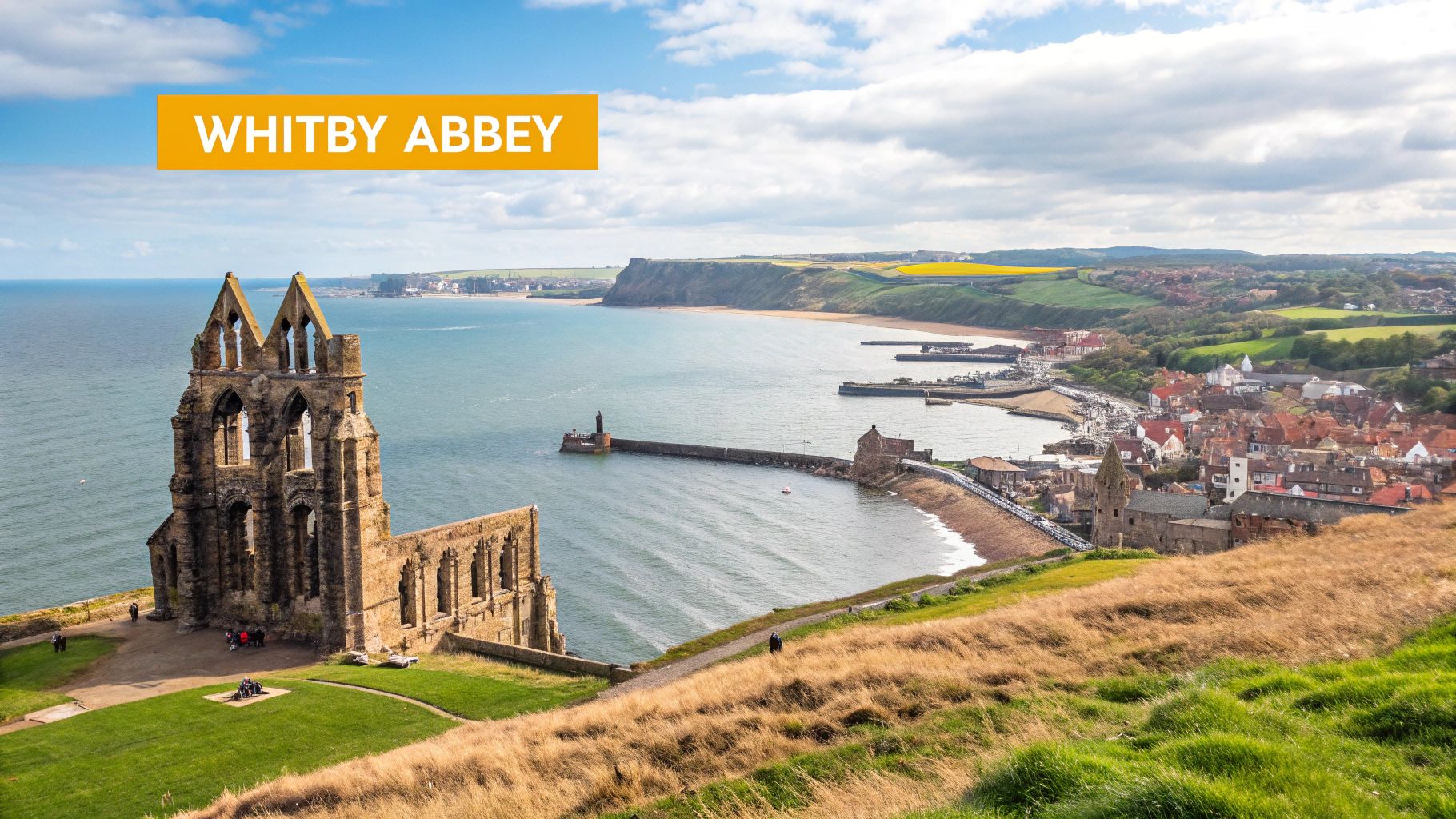 Panoramic view of ancient Whitby Abbey ruins on a cliff overlooking Whitby town and its harbor by the North Sea.