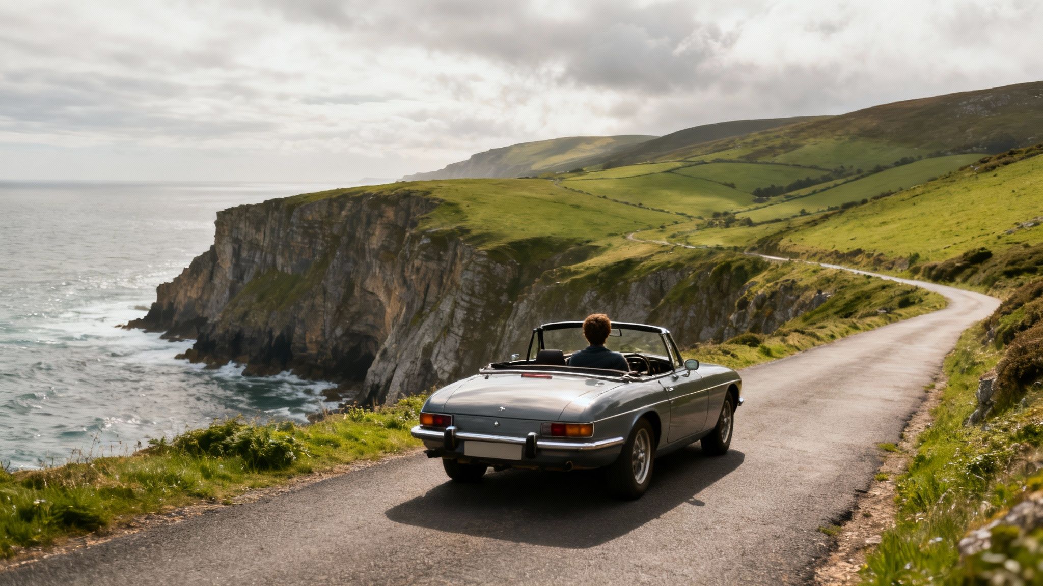 A winding road along the dramatic cliffs of the Irish coast, with the ocean in the background.