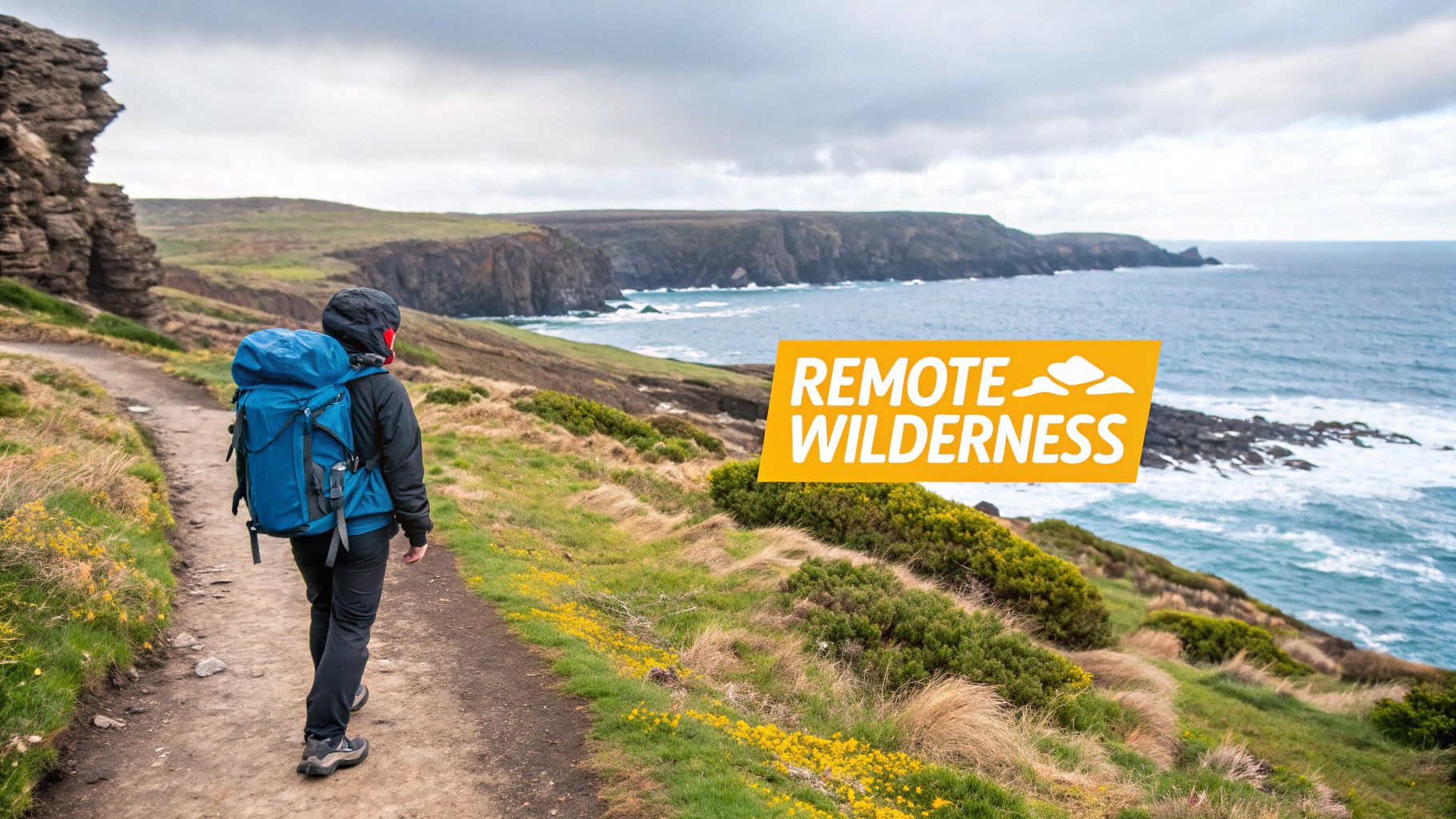 A person with a blue backpack hikes on a coastal path overlooking cliffs and the ocean under a cloudy sky.
