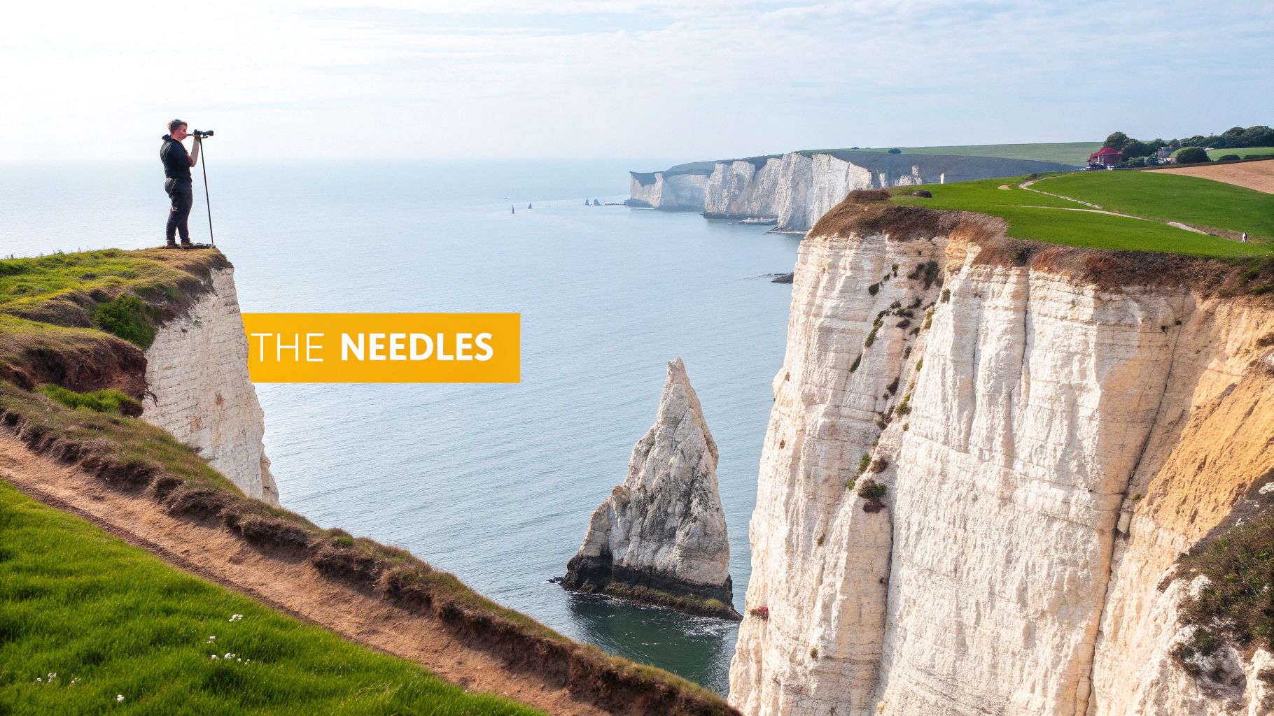 A person views 'The Needles' landmark from a grassy cliff overlooking the sea on the Isle of Wight.