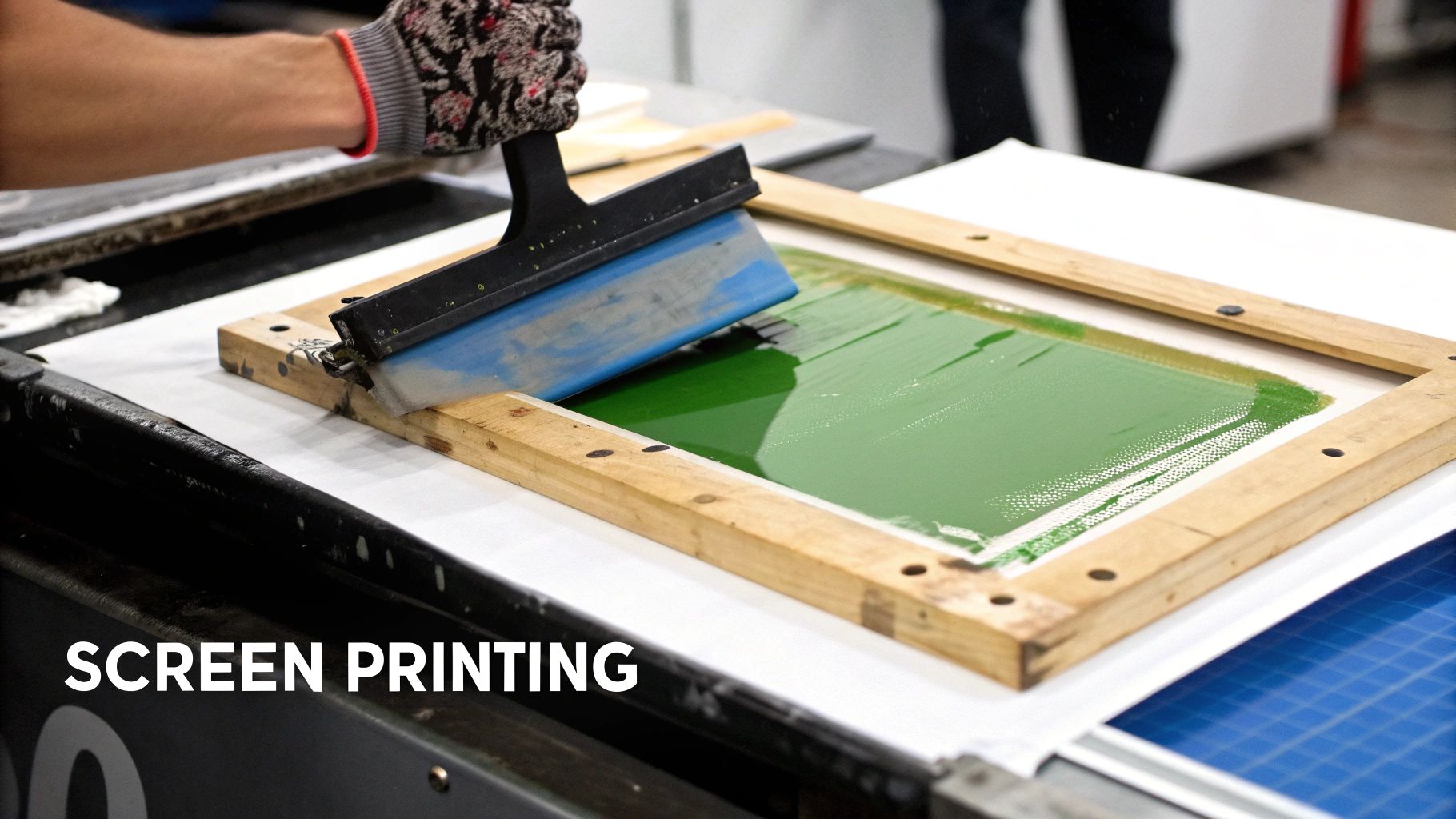A screen printing machine in operation, showing vibrant ink being applied to a t-shirt.