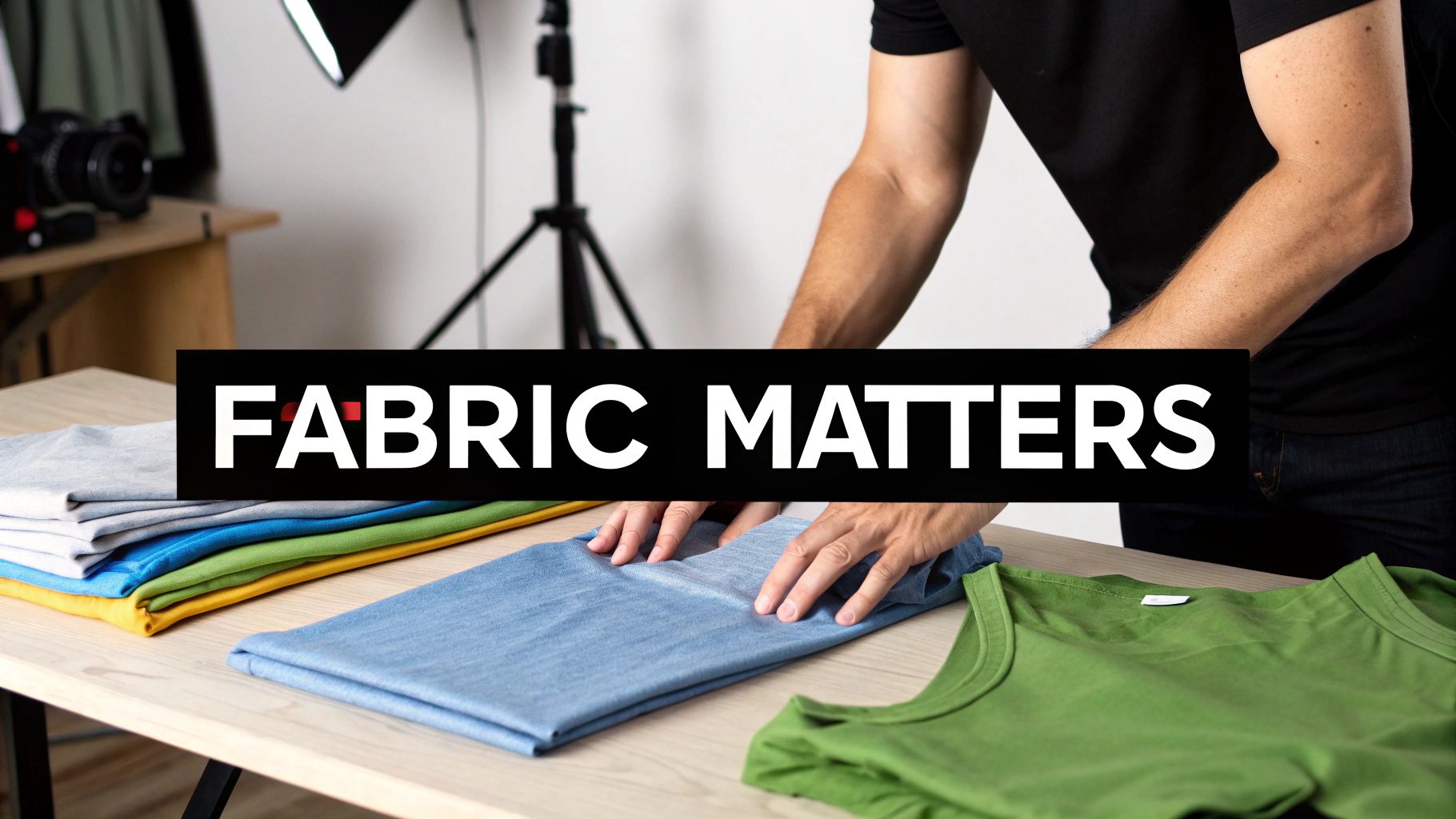 Person folding colorful blank t-shirts on table in professional photography studio setup