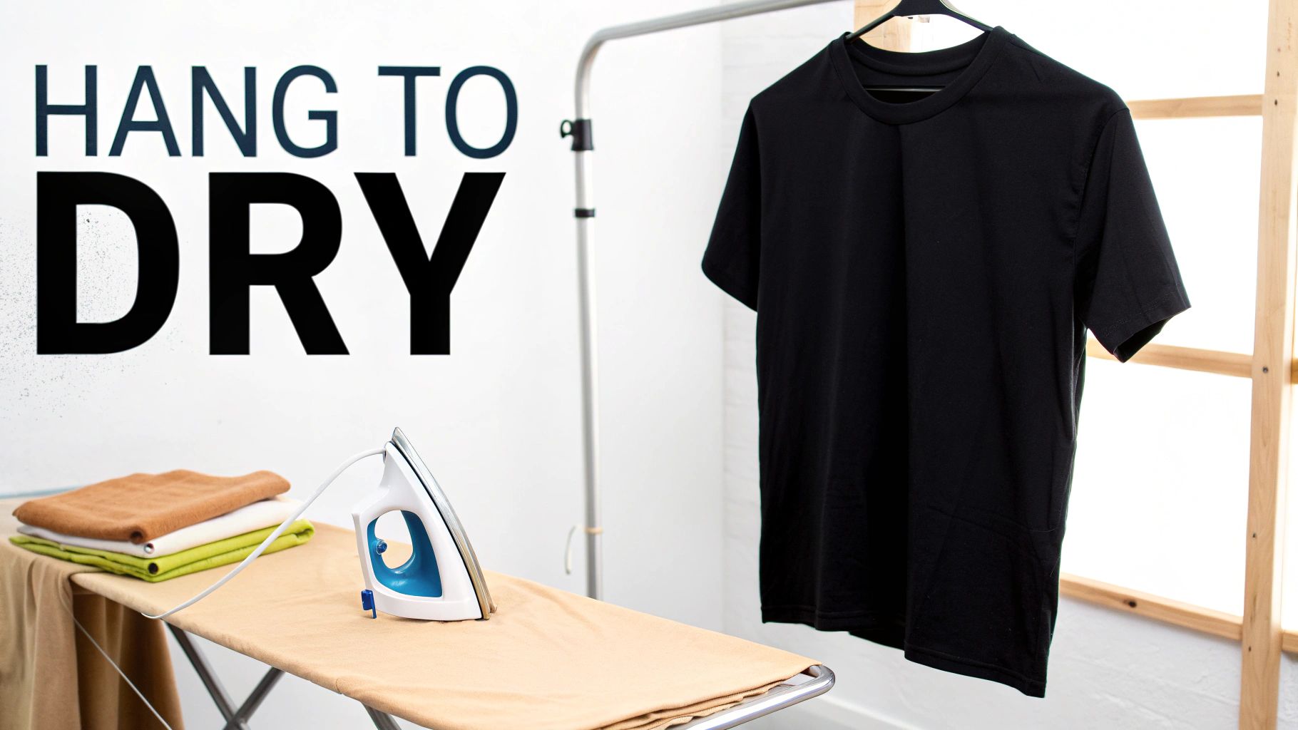 An ironing board with an iron and folded clothes, next to a black t-shirt hanging to dry.