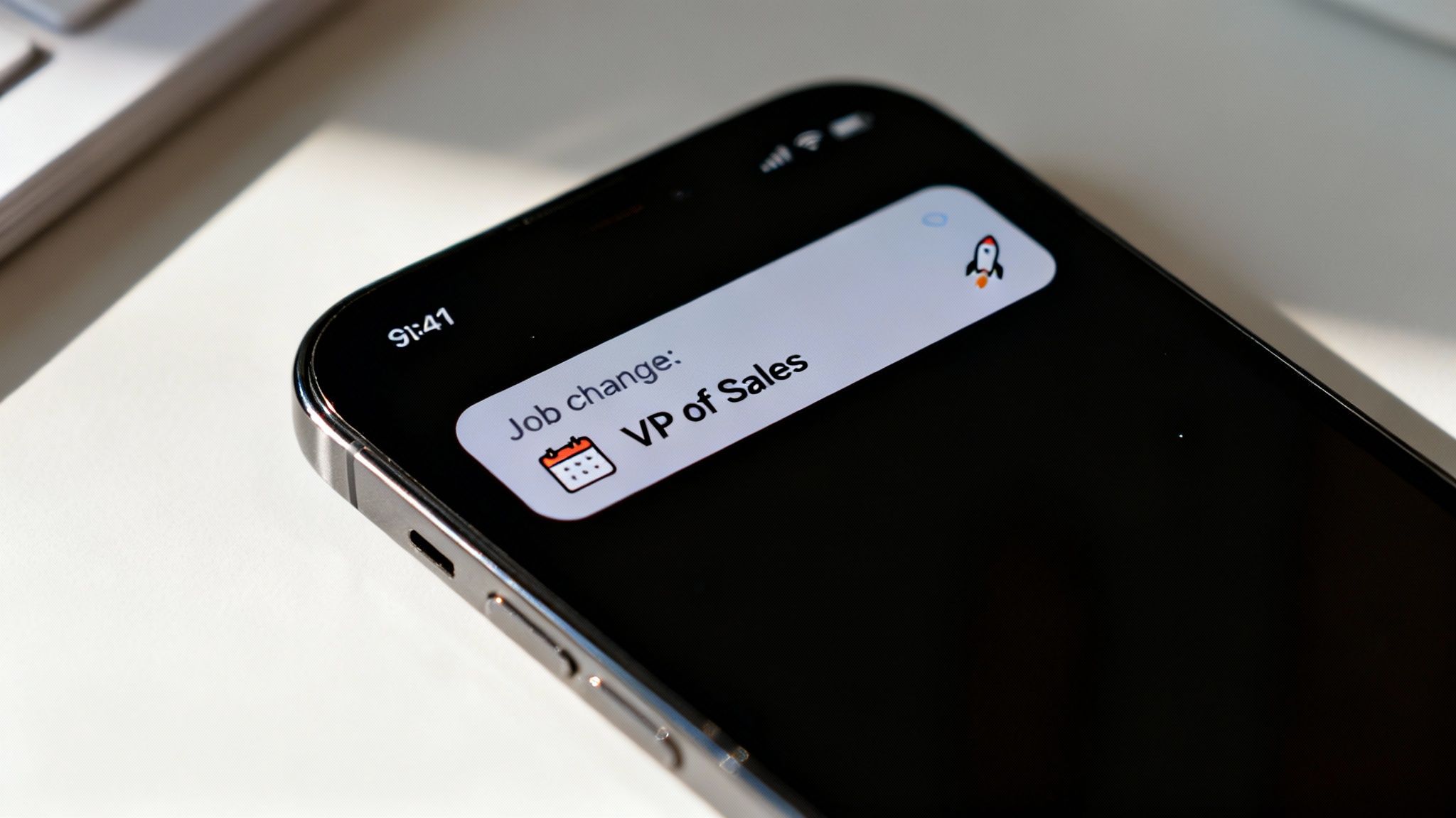Smartphone screen displays a notification: 'Job change: VP of Sales' with calendar and rocket icons.