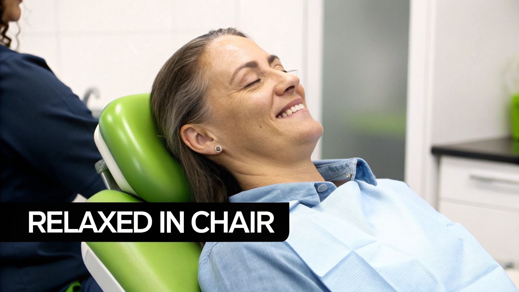 A happy woman with a dental bib smiles, relaxed in a dentist's chair.