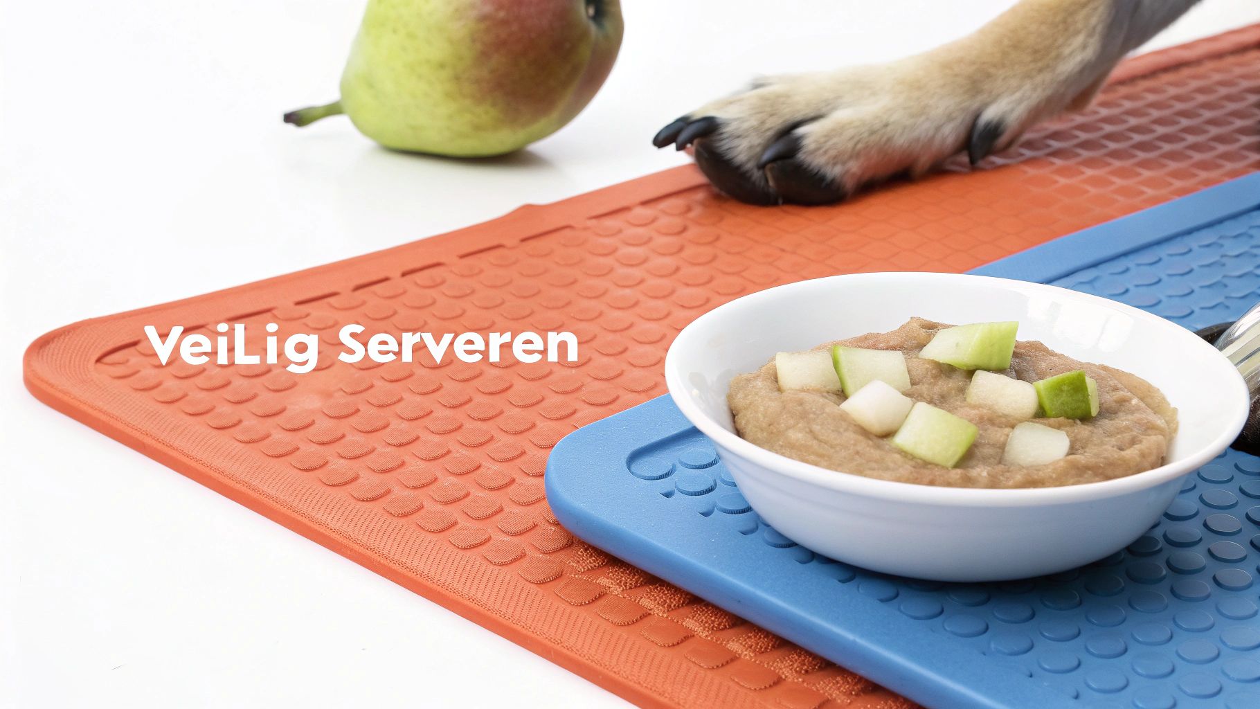 Een hondenpoot bij een peer en een kom met hondenvoer op antislipmatten.