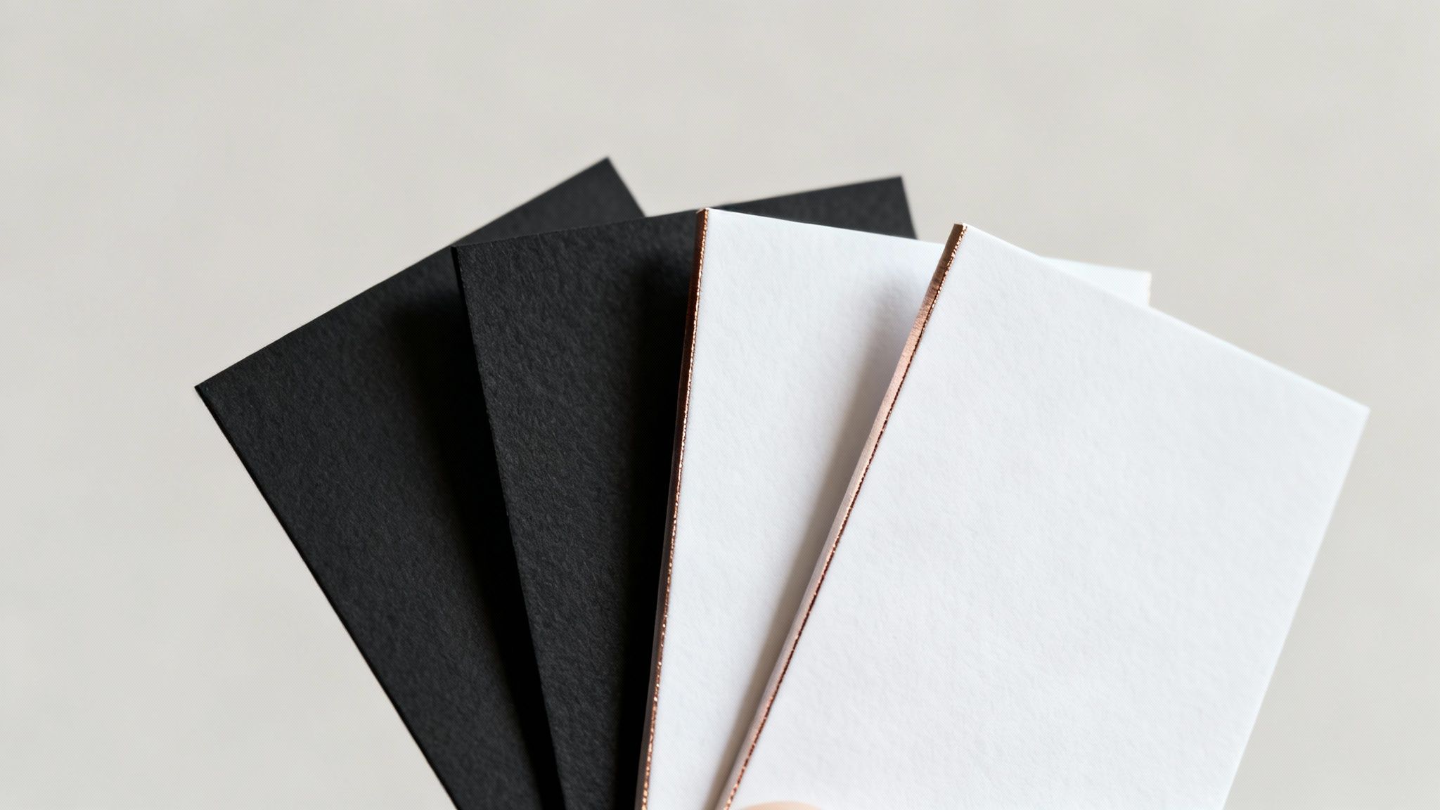 A fan of black and white business cards with elegant rose gold foil edges.