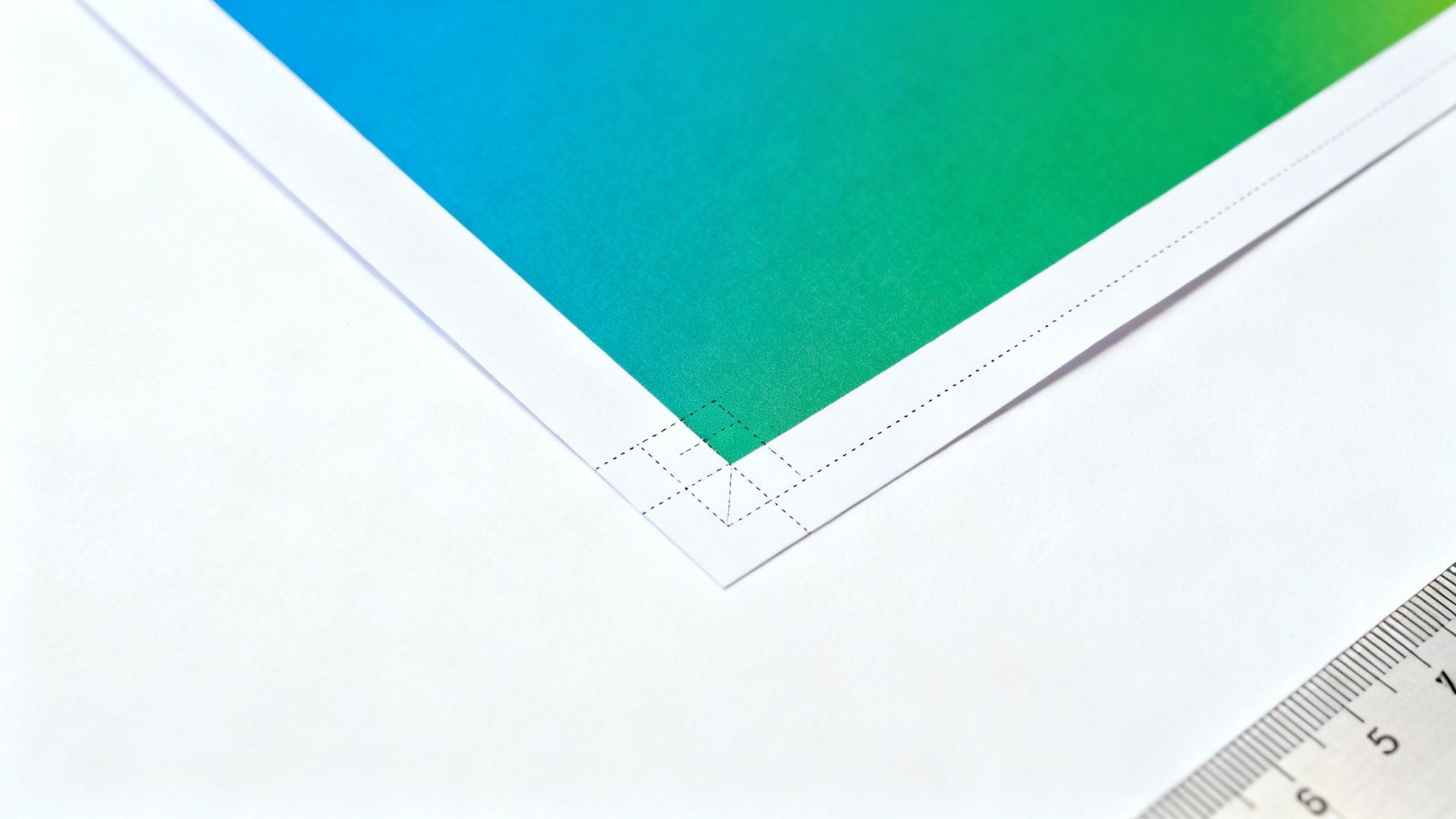 Close-up of a printed paper with a blue-green gradient, showing trim and bleed marks.
