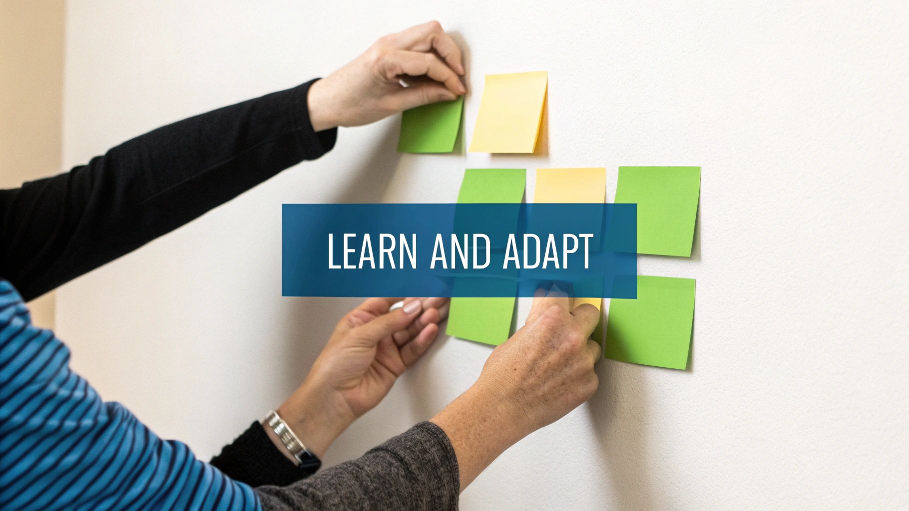 Two people collaborating, placing colorful sticky notes on a white wall with the text 'LEARN AND ADAPT'.