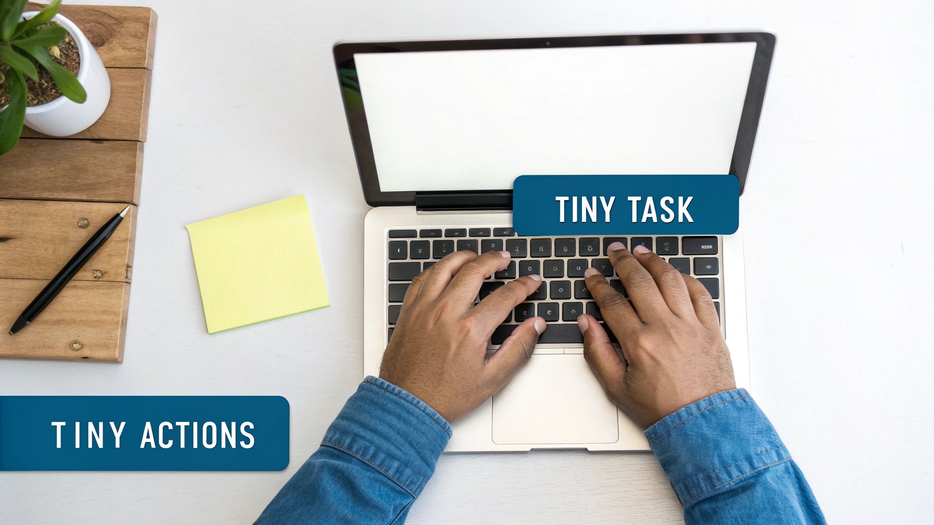 Overhead shot of hands typing on a laptop with 'TINY TASK' and 'TINY ACTIONS' text on a desk.