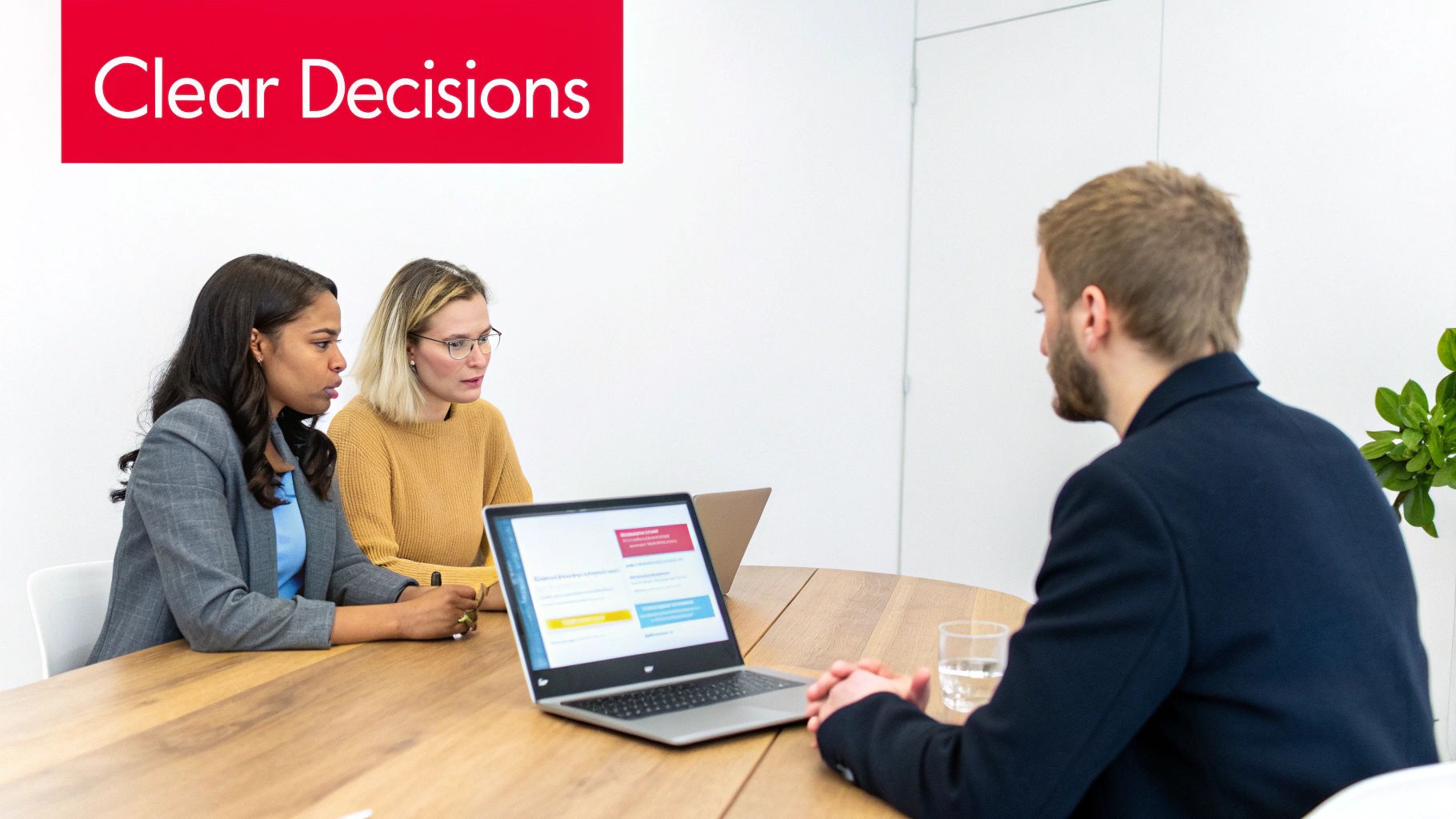 Three professionals, two women and one man, in a meeting or interview setting with a laptop.