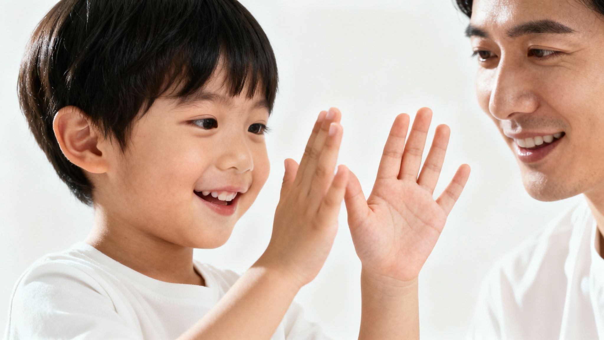 A happy Asian father and son playing together, both smiling joyfully.