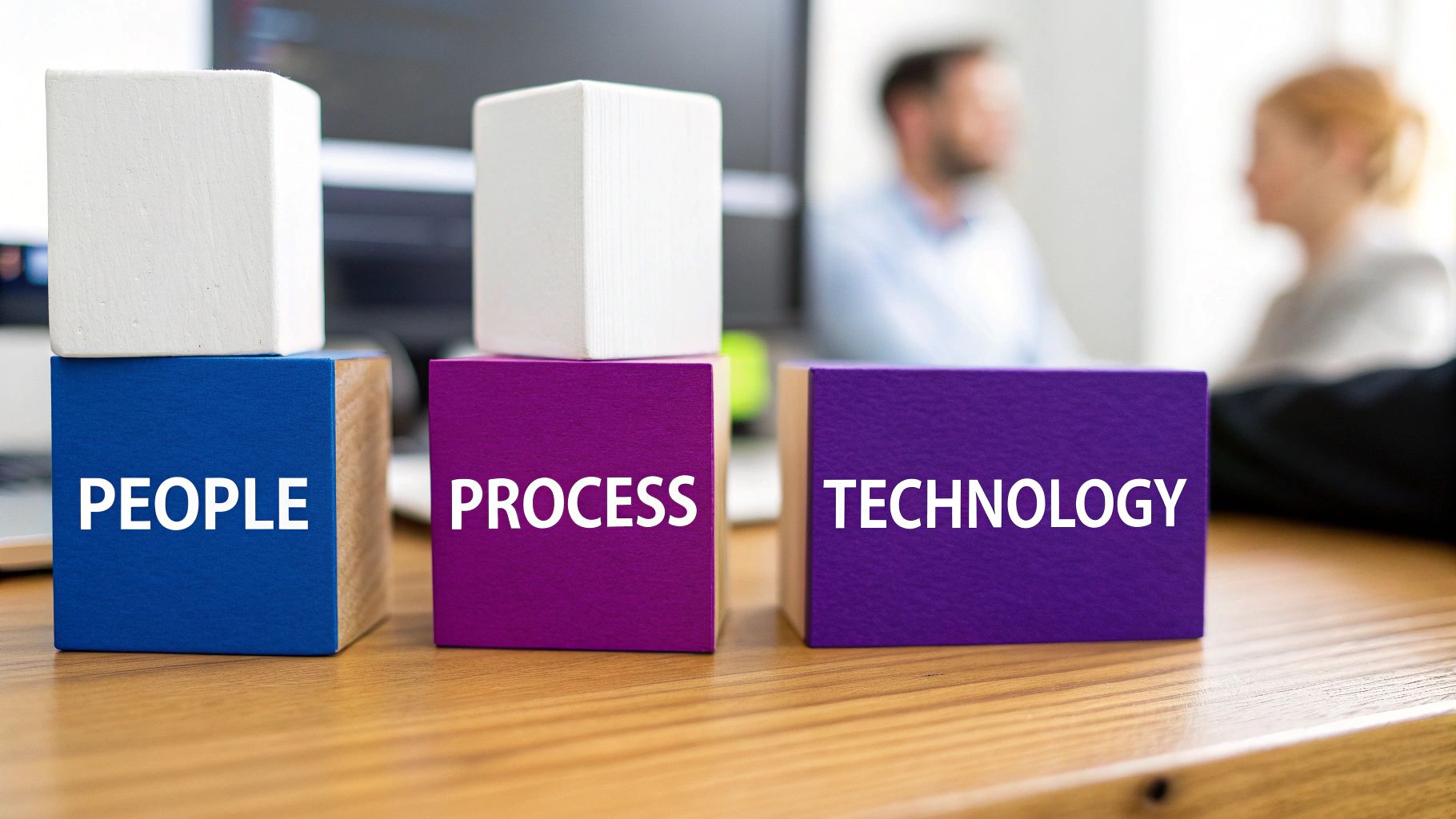 Blocks on a table spelling PEOPLE, PROCESS, TECHNOLOGY, representing core business transformation pillars.