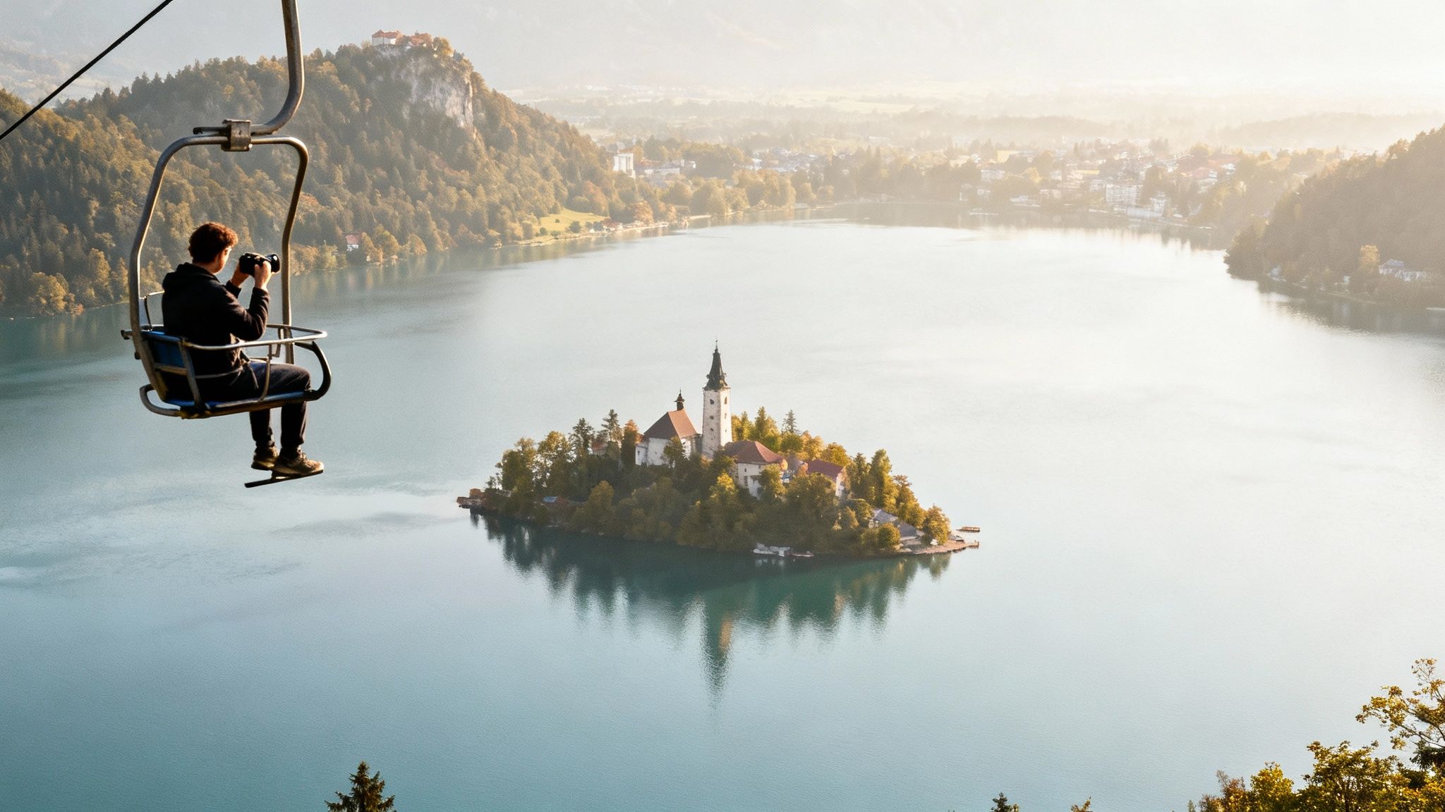 A person on a chairlift photographs the iconic island church in the middle of Lake Bled.