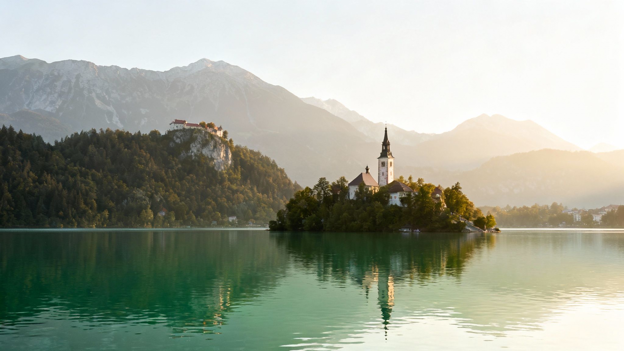 Picturesque sunrise over Lake Bled, Slovenia, featuring the iconic island church and Bled Castle.