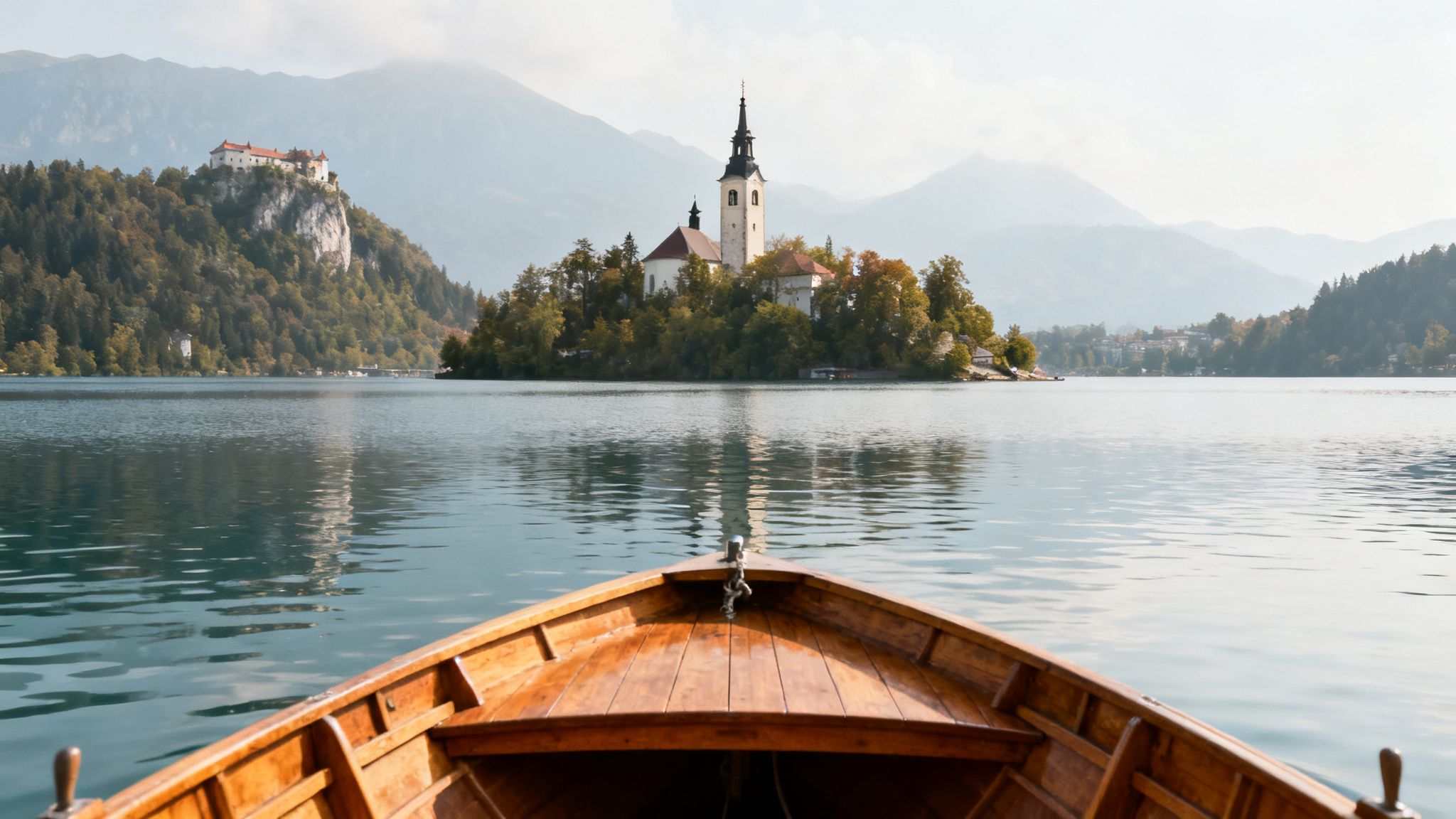View from a wooden boat on Lake Bled, featuring the island church and Bled Castle.