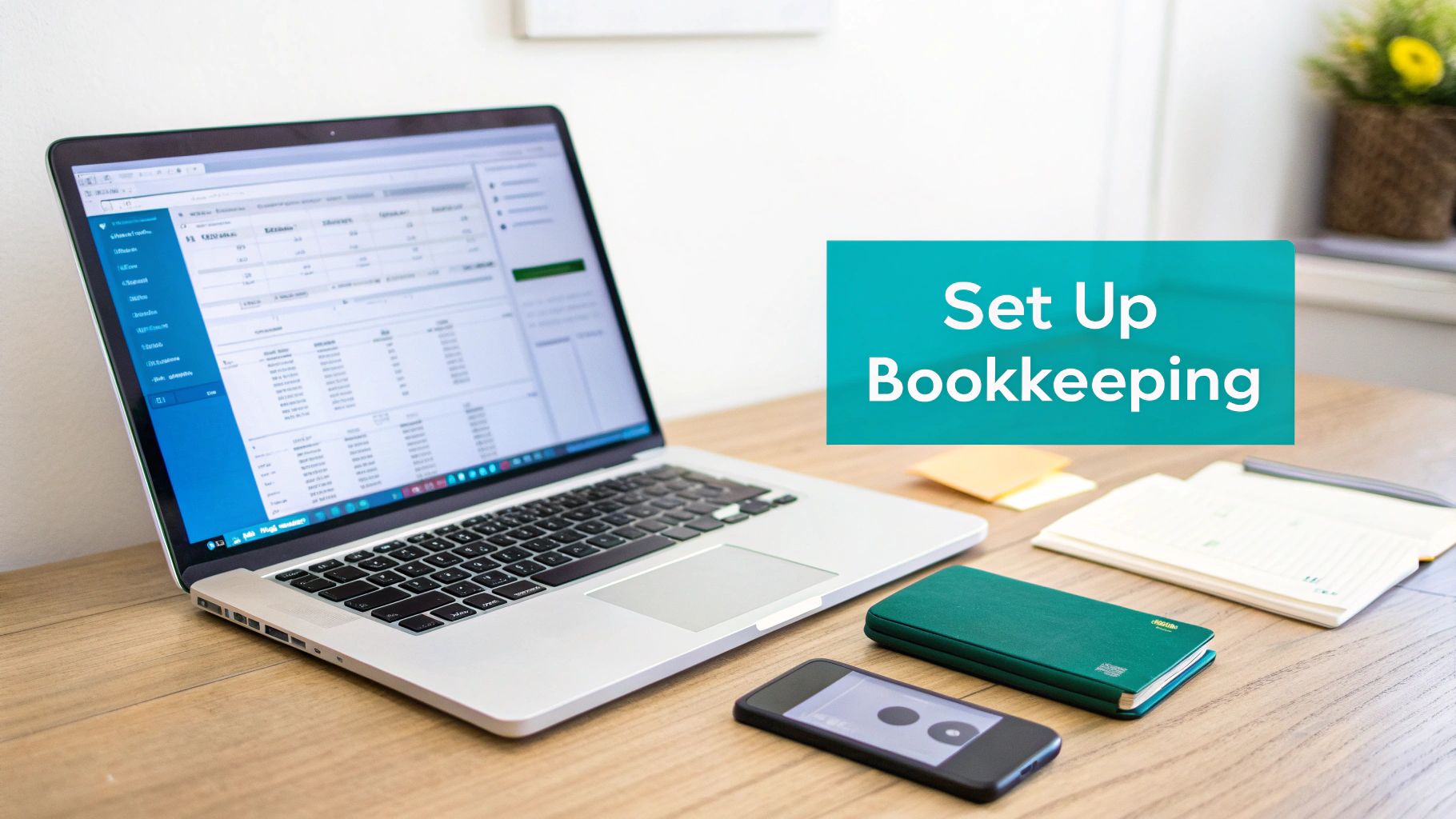 A desk setup with a laptop showing bookkeeping software, notebooks, and a smartphone.